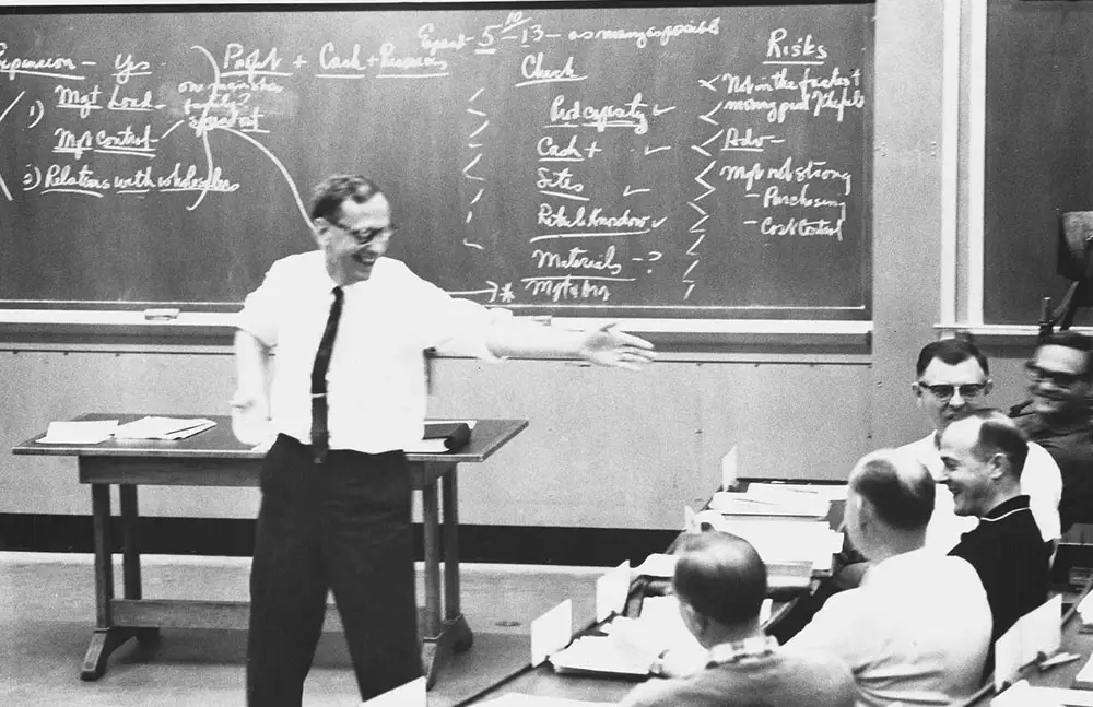 Black and white photograph of HBS Professor C. Roland Christensen gesturing toward a student while teaching.