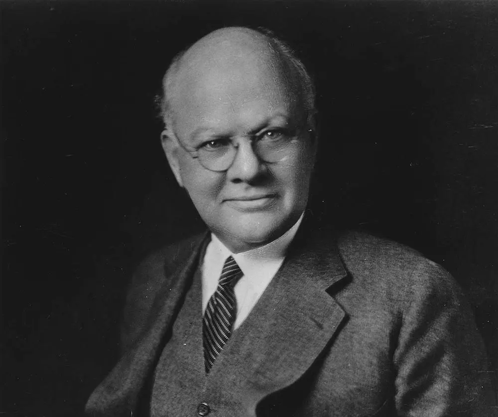 Dean Wallace B. Donham in a three piece suit, striped tie, and spectacles.
