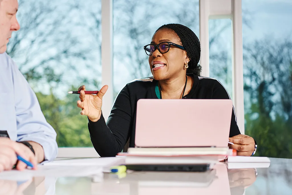 Black female participant sits in front of a computer and leads discussion inside a meeting room