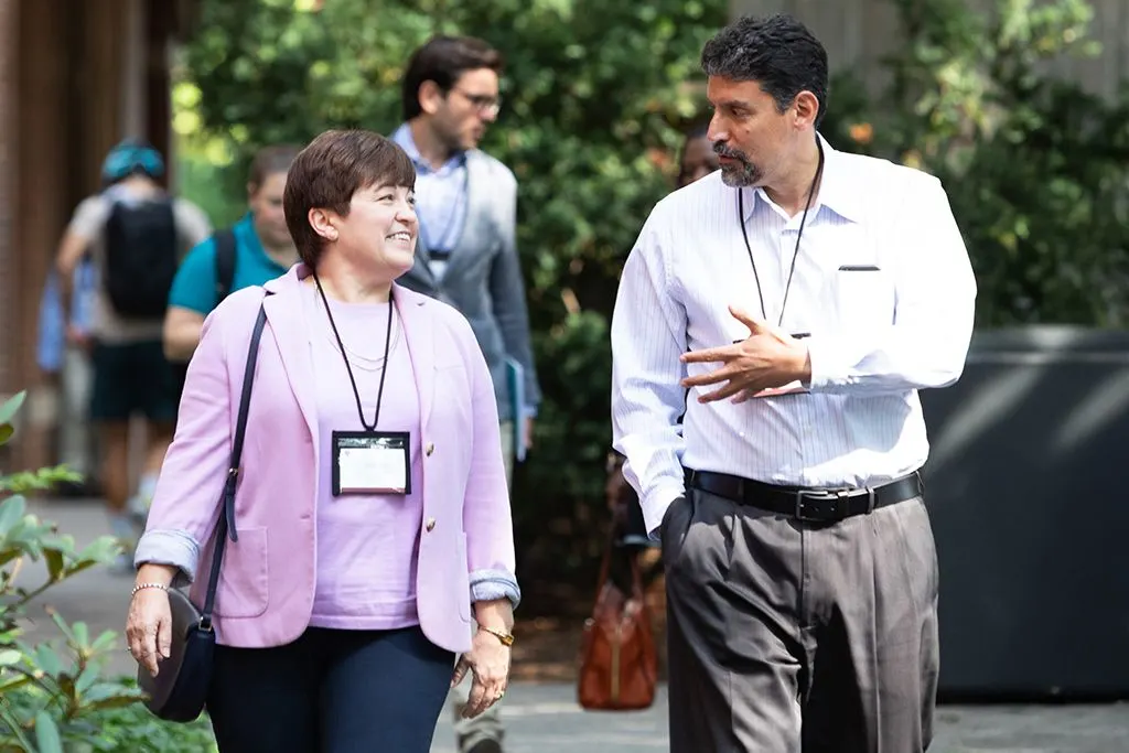 A male and female participating executive talk as they walk through the HBS campus