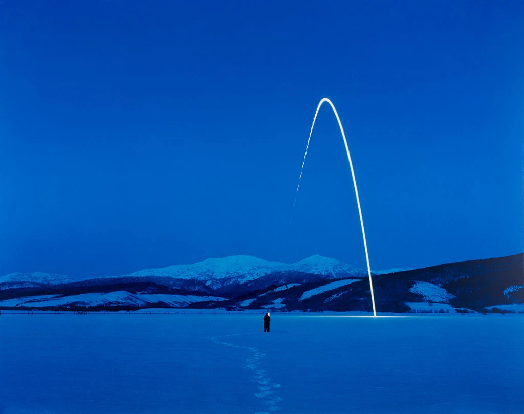 Nighttime landscape in Idaho lit by a beam of light, evoking a distress signal in a remote natural setting.