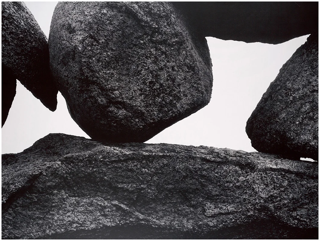 Large, textured boulders stacked in dramatic balance against a pale sky, emphasizing form and contrast.