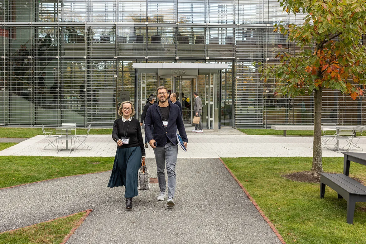A male and a female participant walk out of Tata and onto the Harvard Business School campus