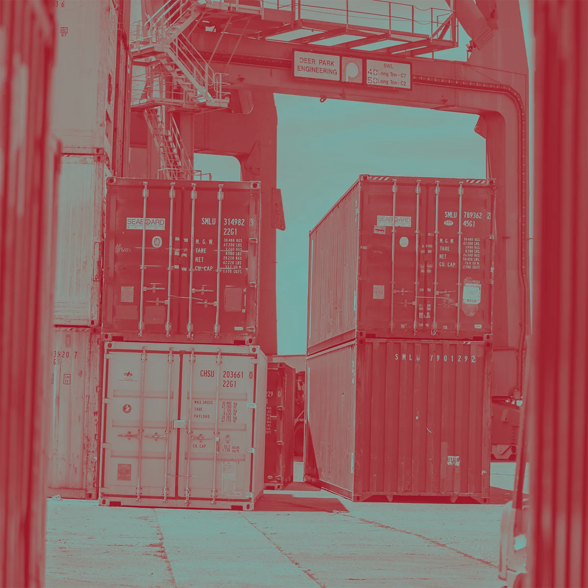 Duotone image with shipping containers waiting on a cement dock.
