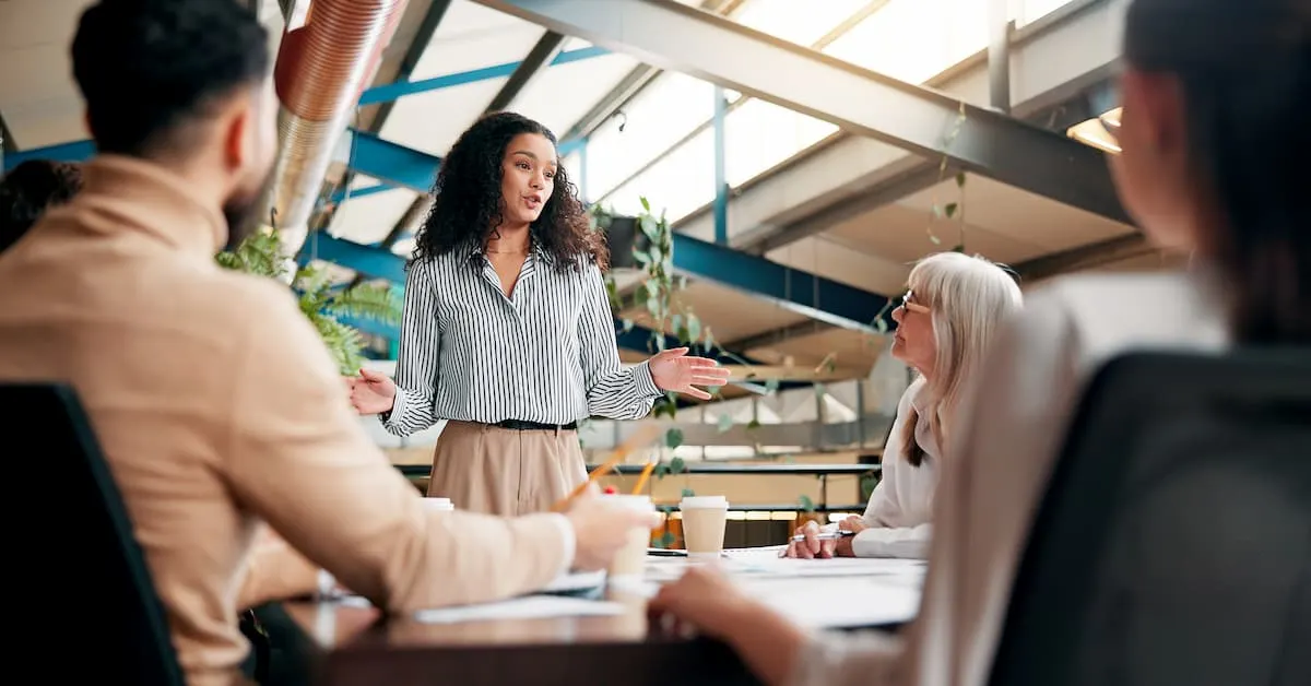Woman presenting in front of her coworkers in a board room. 
