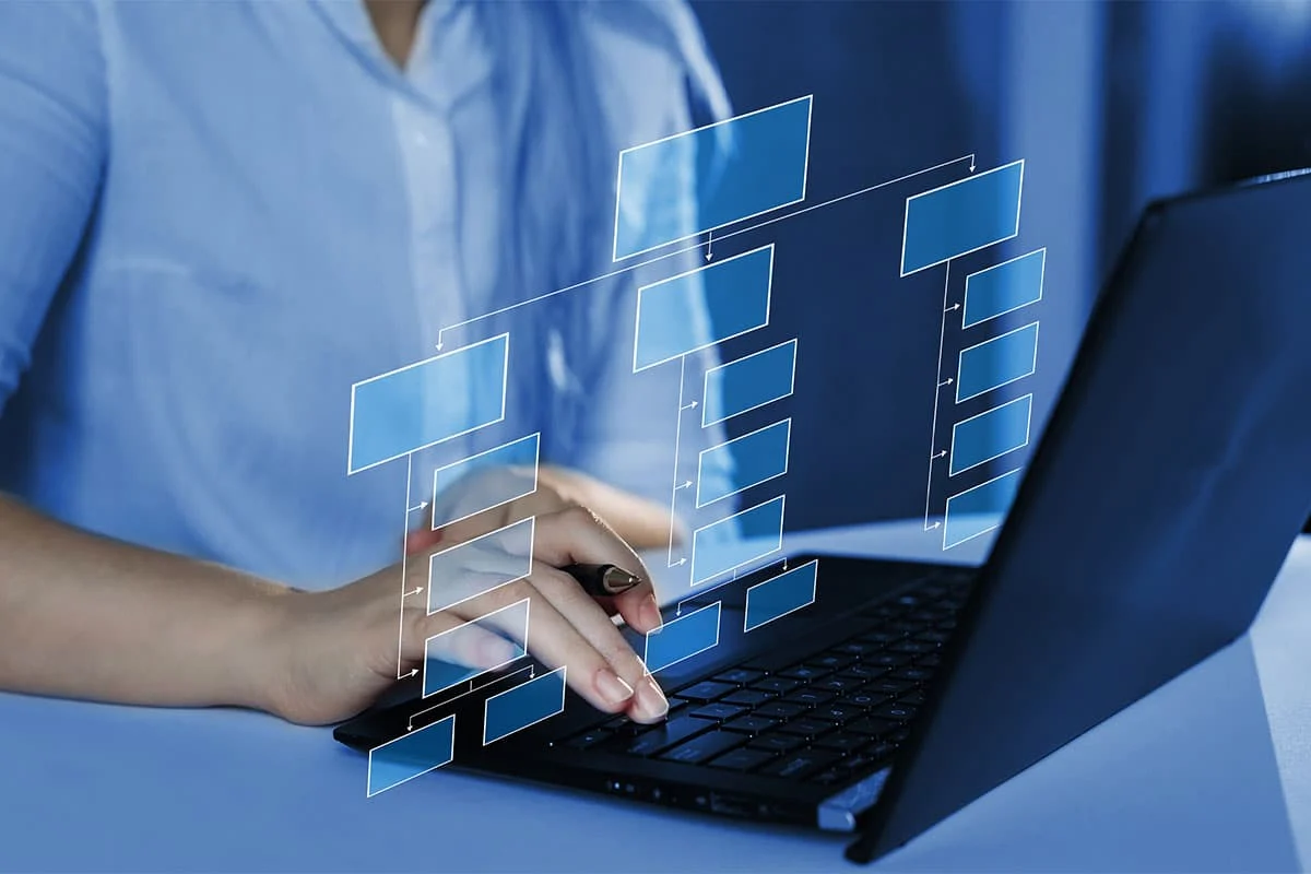 Person working on a laptop with a digital decision-tree diagram displayed on screen, illustrating AI data modeling and analysis.