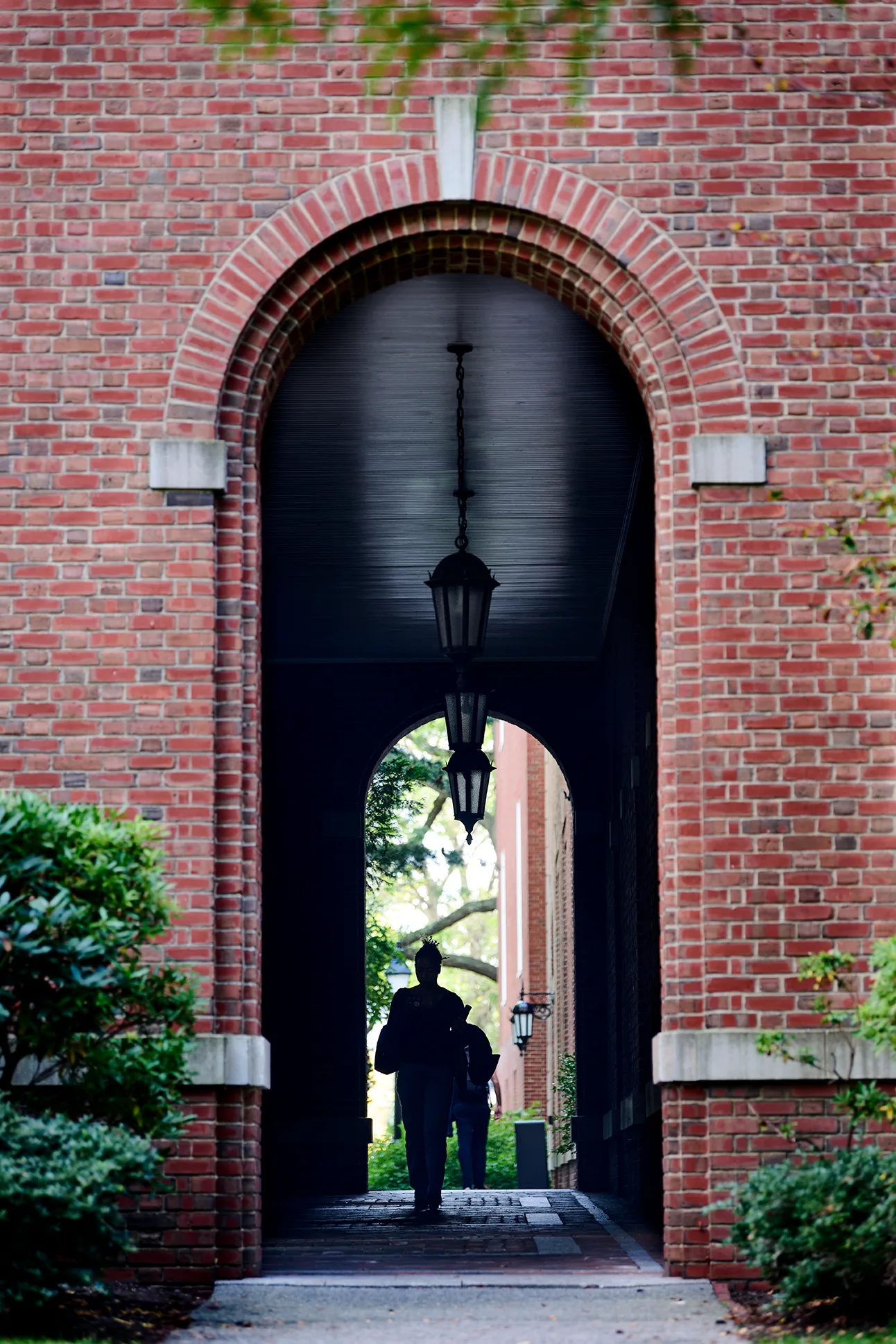 A person's silhouette in a curved brick historic building archway on HBS campus