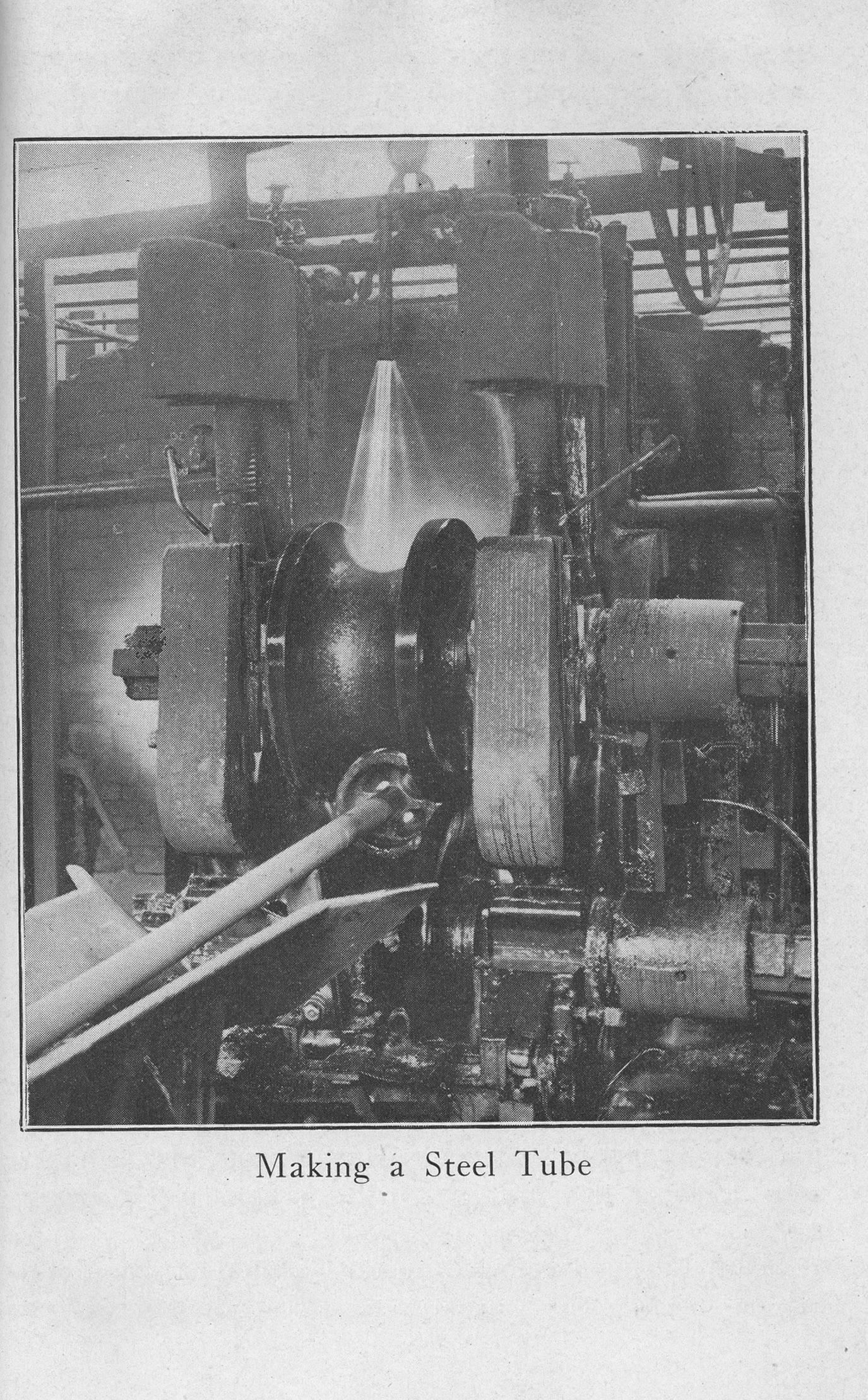 Industrial machinery forming a steel tube in a U.S. Steel plant, with metal being shaped between large rollers.