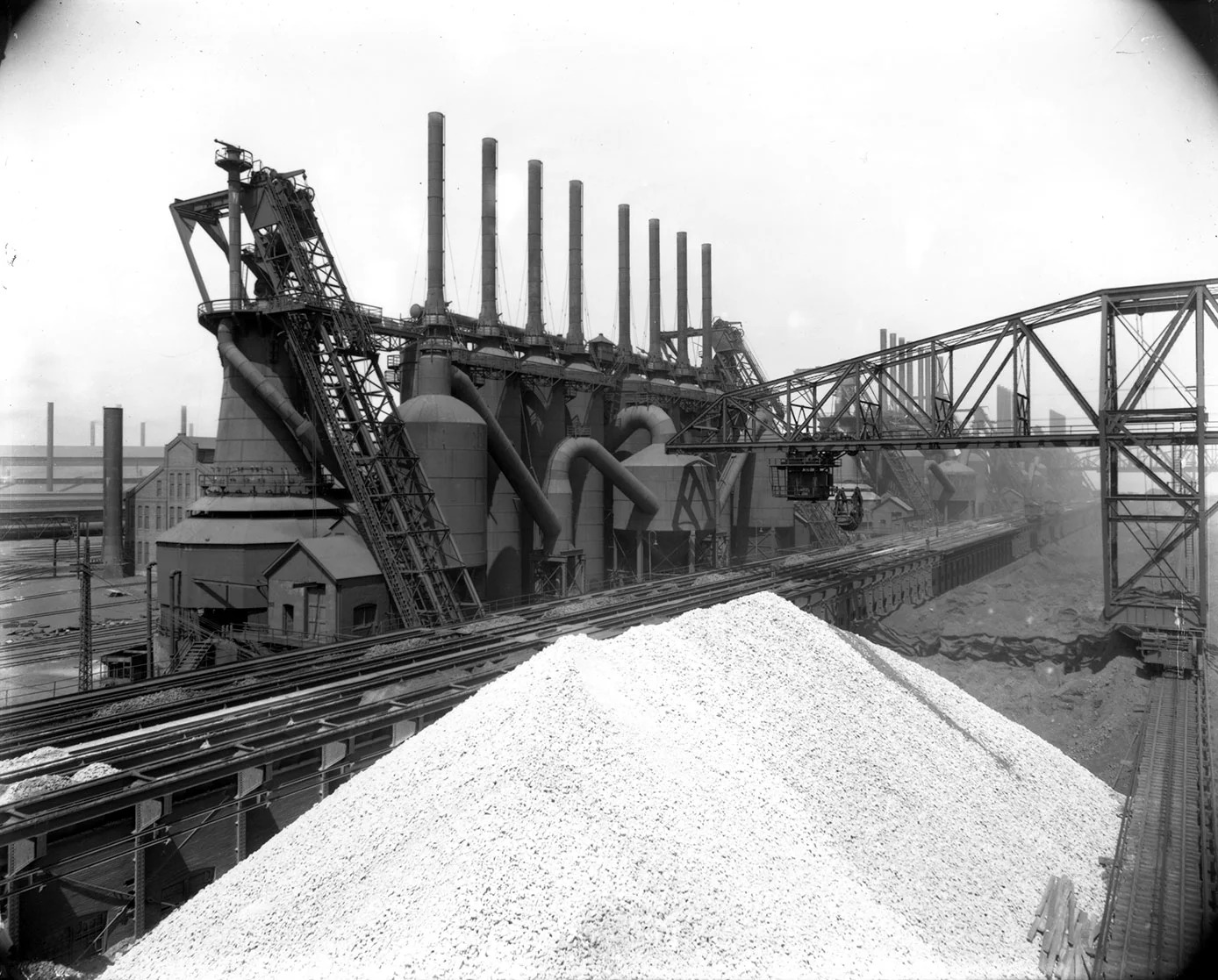 Large blast furnace complex with multiple smokestacks, conveyor systems, and a white ore pile in the foreground, dated April 30, 1913.