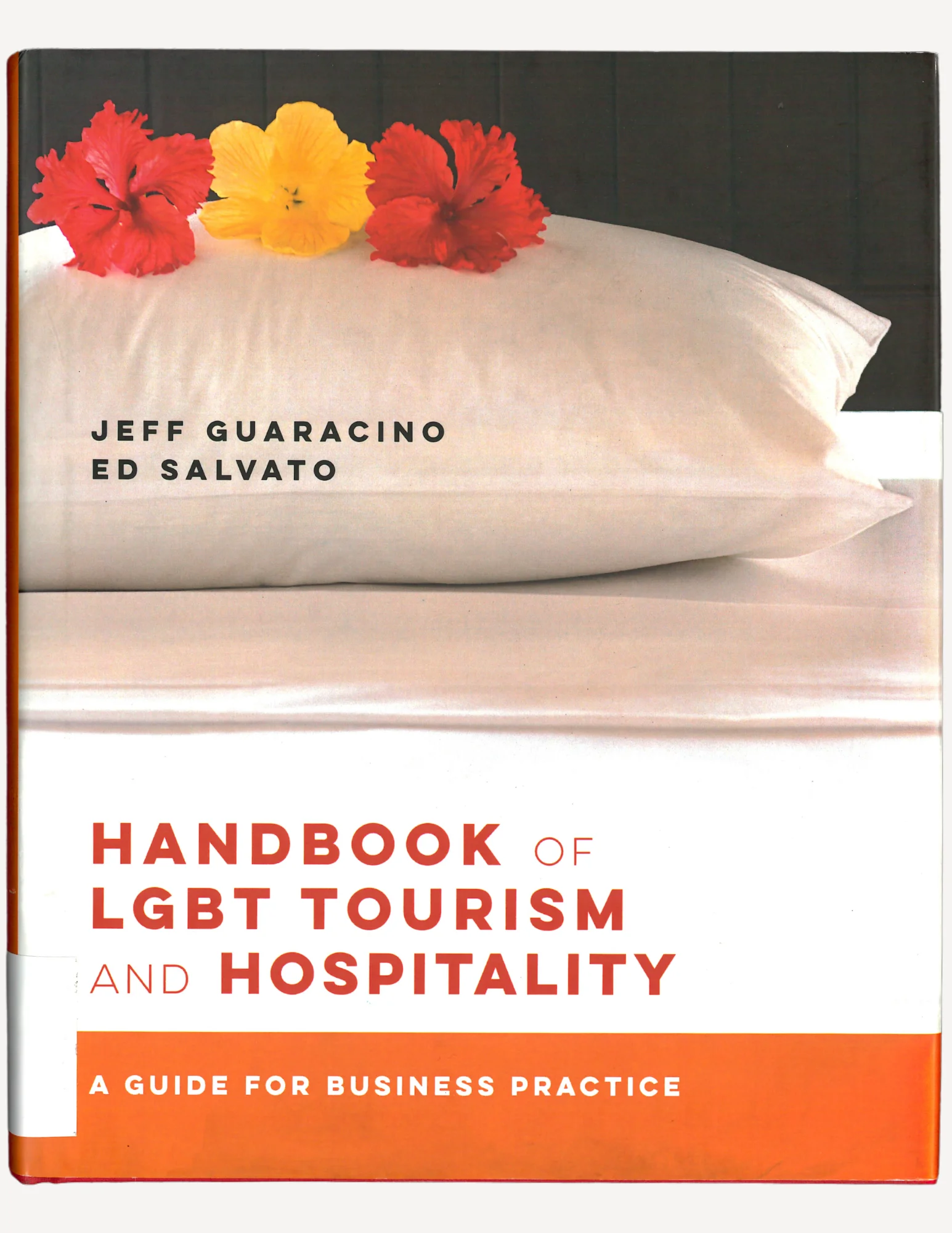 A book cover of a hotel bed with a pillow and three hibiscus flowers: two red, one yellow in the center.