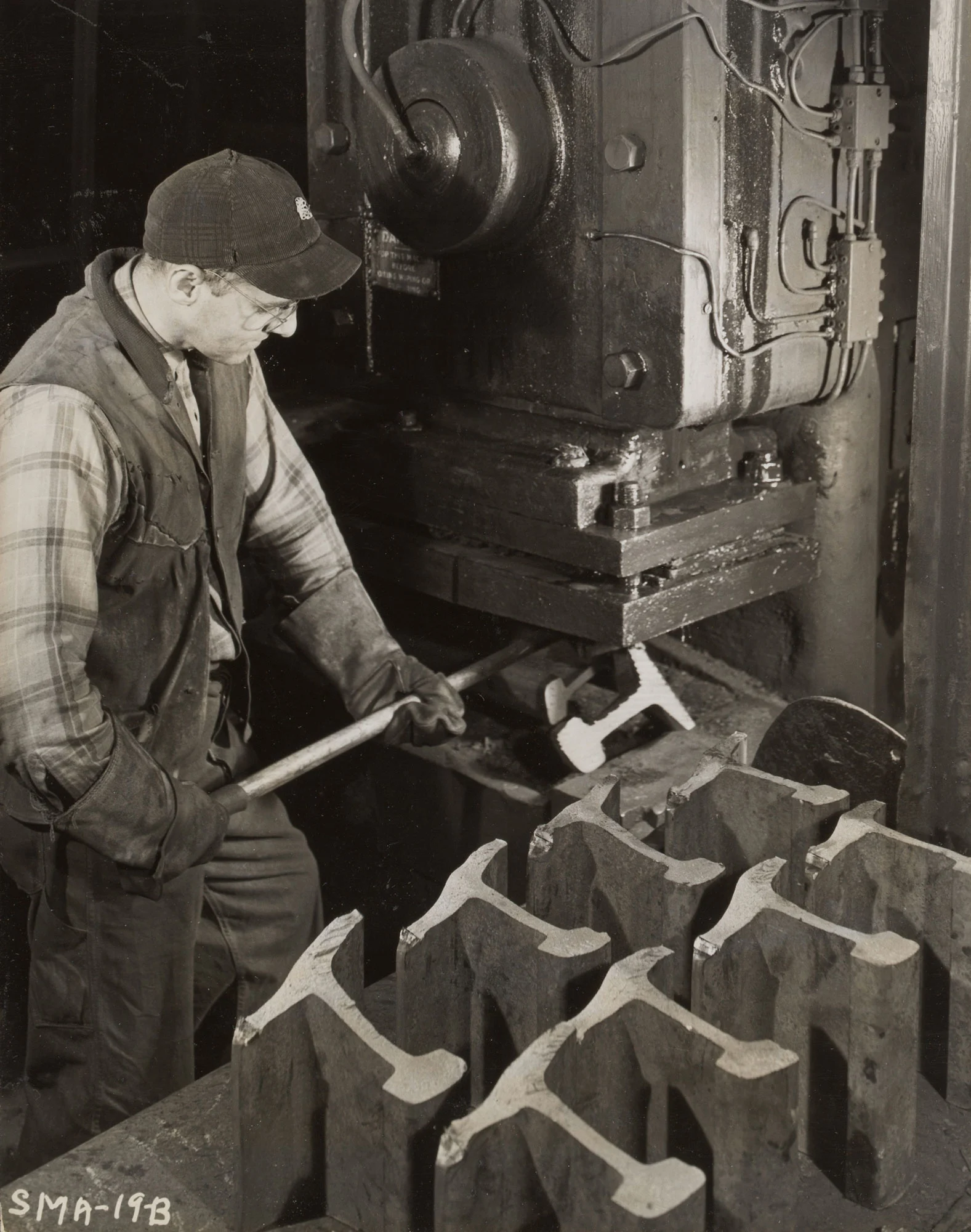 Inspector performs nick and break test on rail section under hydraulic hammer at Gary Steel Works.