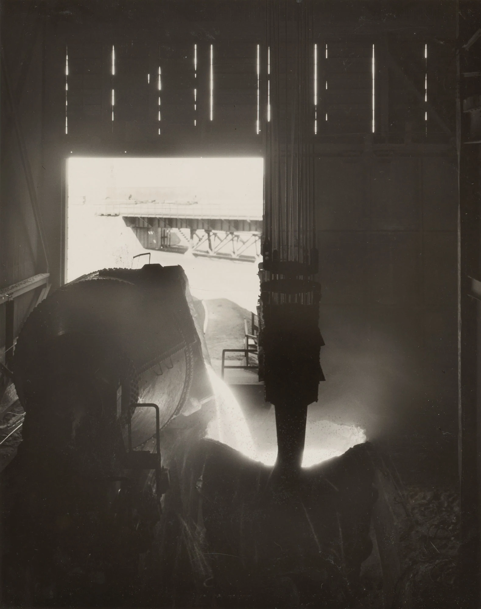 Molten iron pours from large ladle into transfer vessel at Gary Steel Works open hearth facility.
