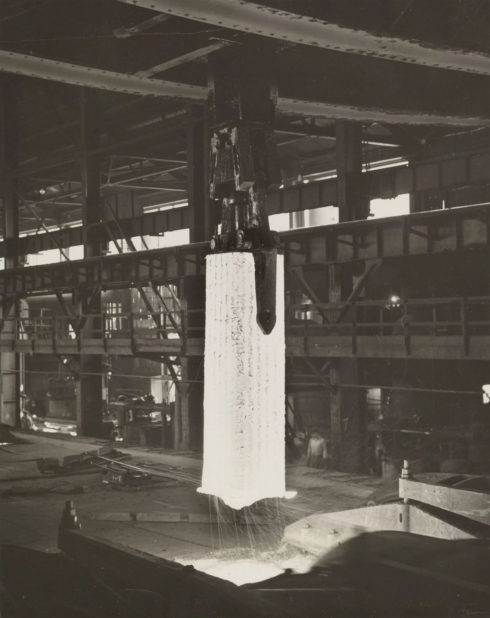 Glowing steel ingot lifted from soaking pit for rolling at Gary Steel Works.