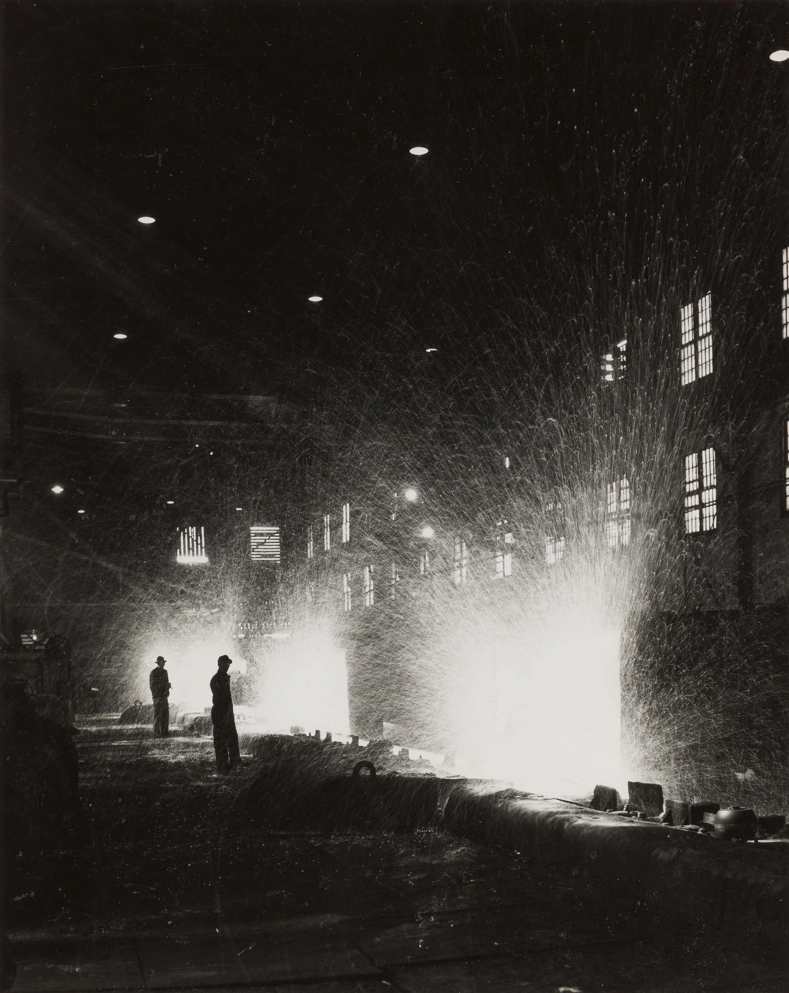 Workers stand near hot saws as sparks fly while steel rails are cut into 39-foot sections at Gary Steel Works.
