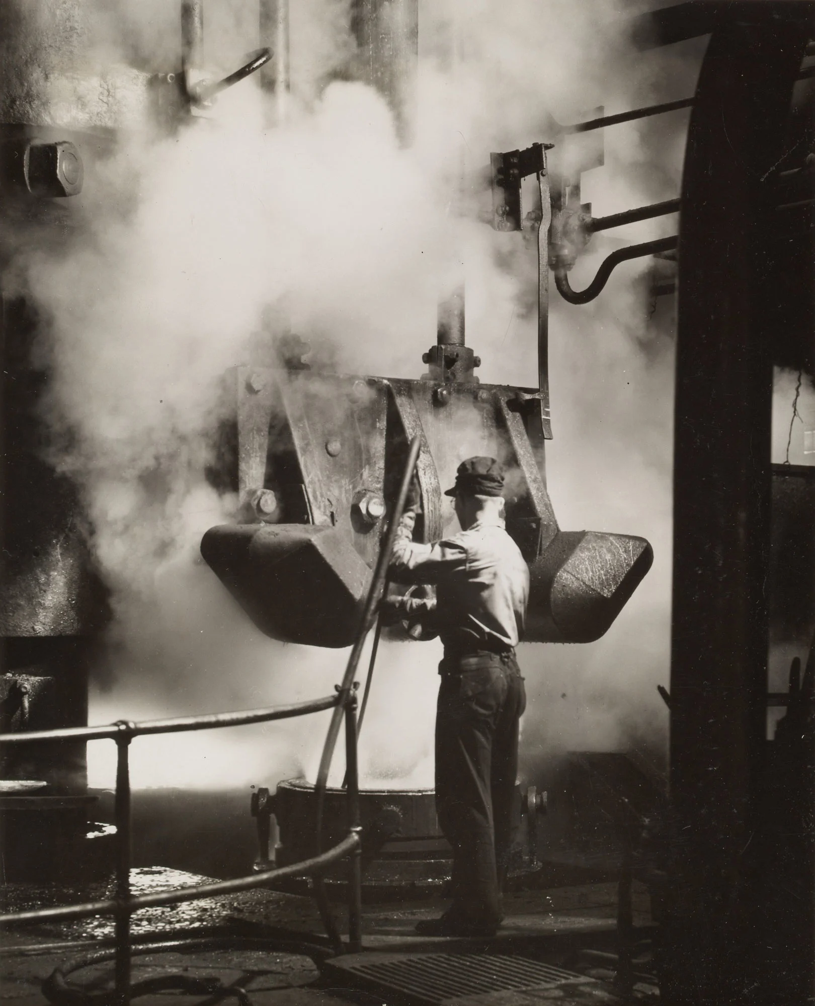 Worker operates 10,000-ton hydraulic press surrounded by steam in the wheel mill at Gary Steel Works.