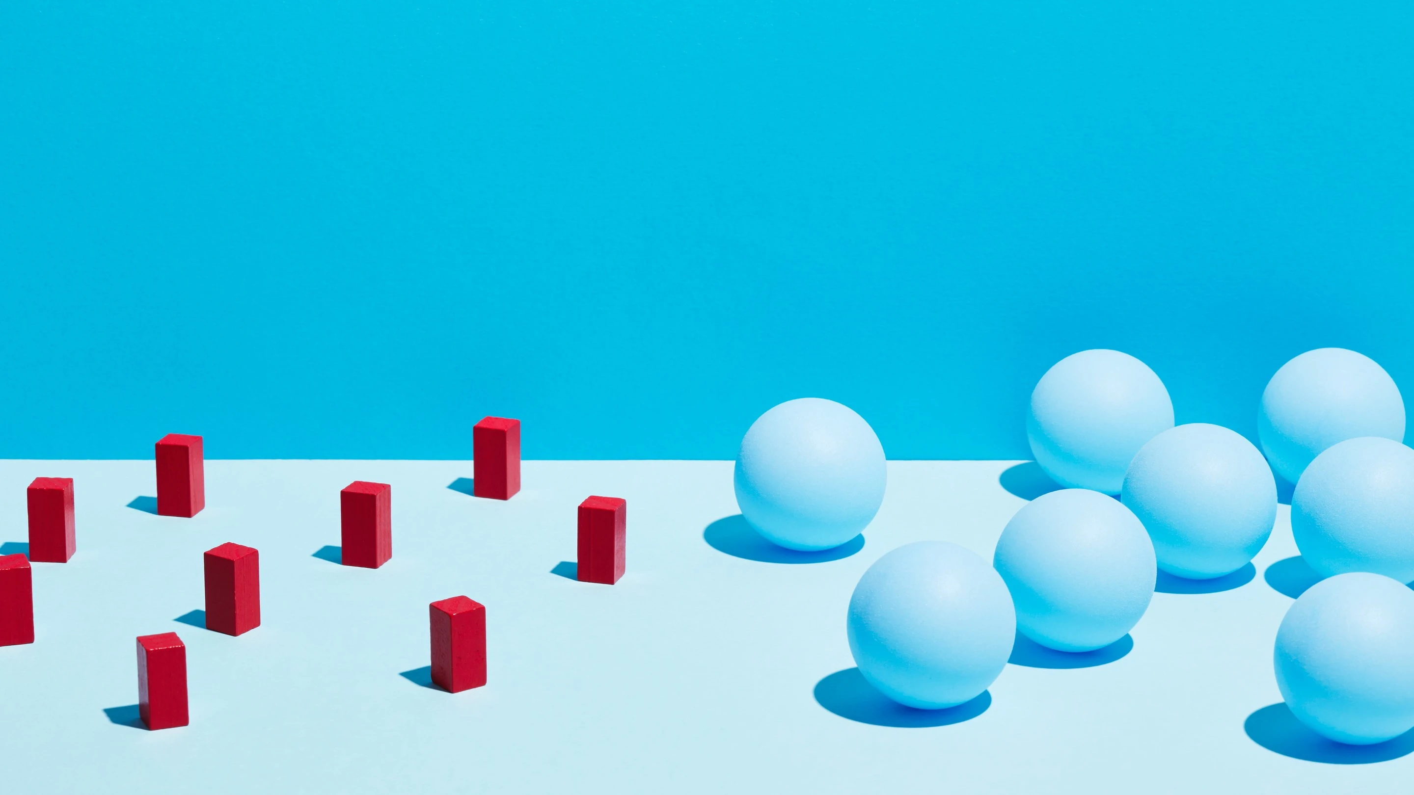 A conceptual image features red rectangular blocks and blue spheres on a split-tone blue background, symbolizing contrast and group dynamics