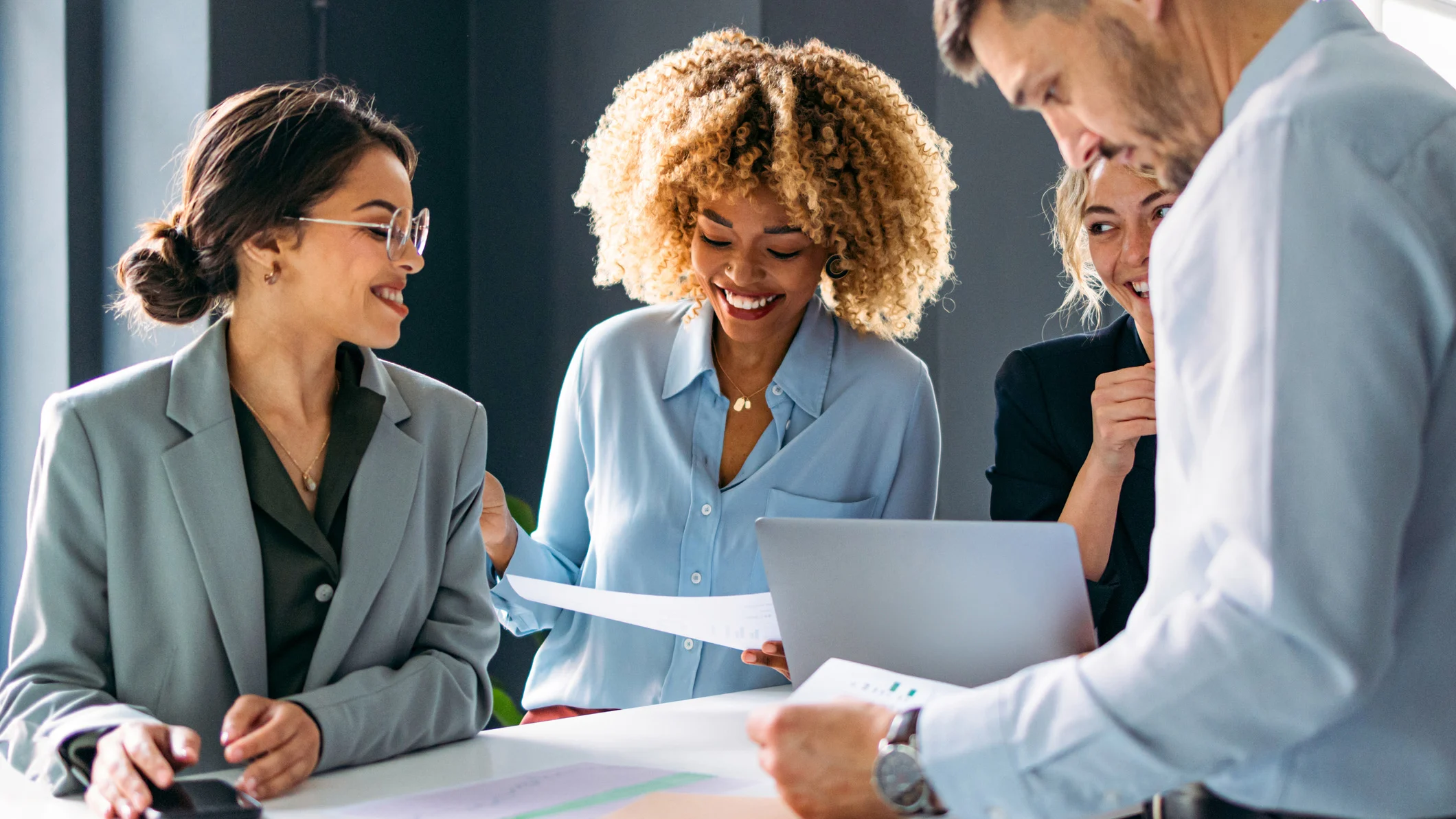 A diverse project group collaborates in a modern office, reviewing documents and discussing strategies during a business meeting