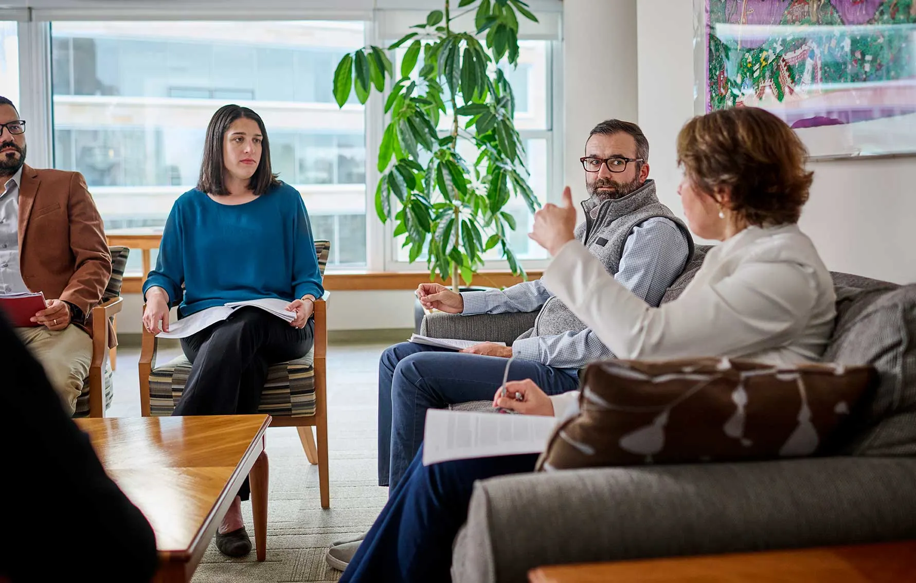 A group of Executives engaged in a discussion in a modern office setting, holding documents and taking notes