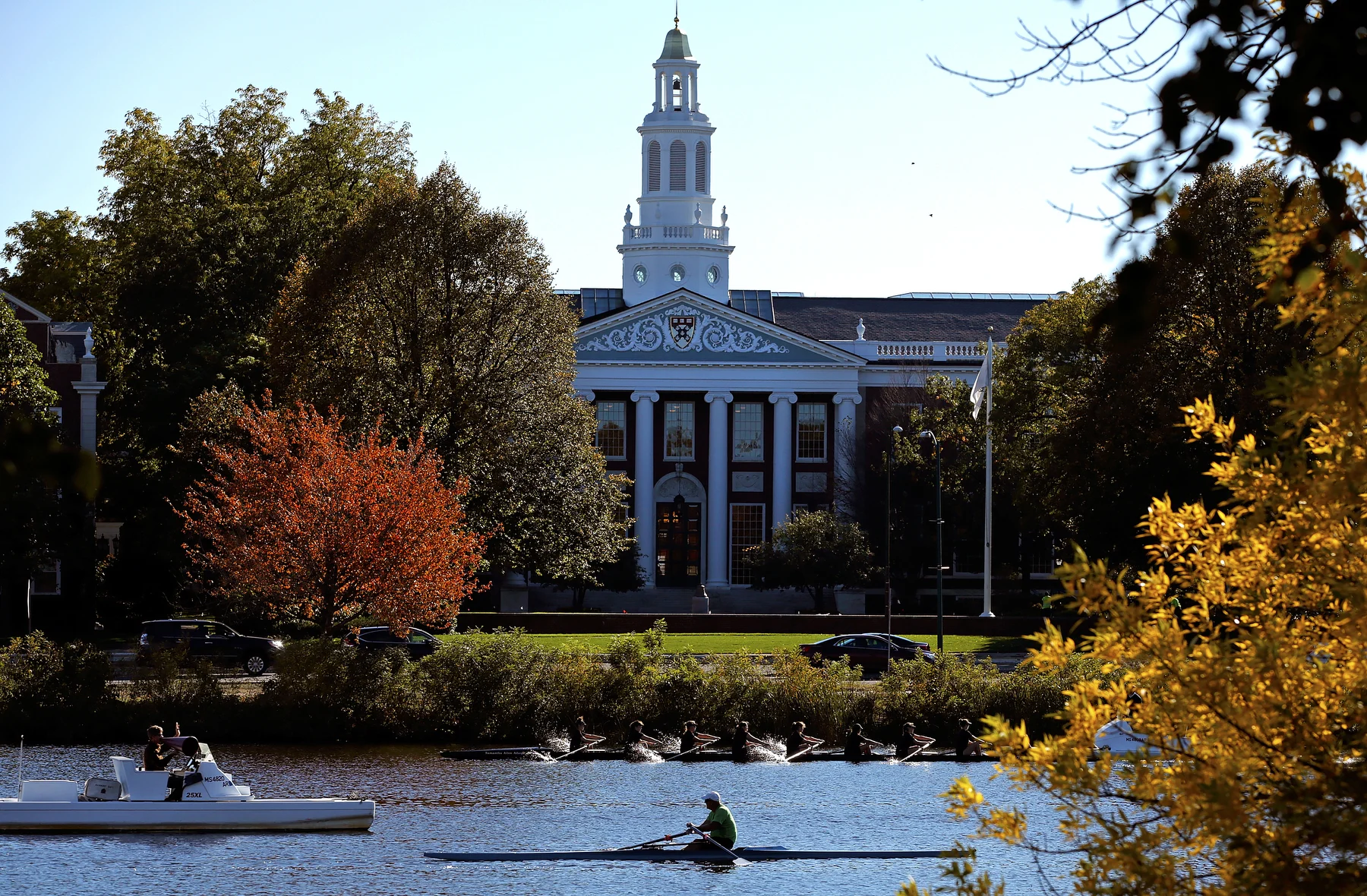 Rowers crew on the Charles river in front of Baker library