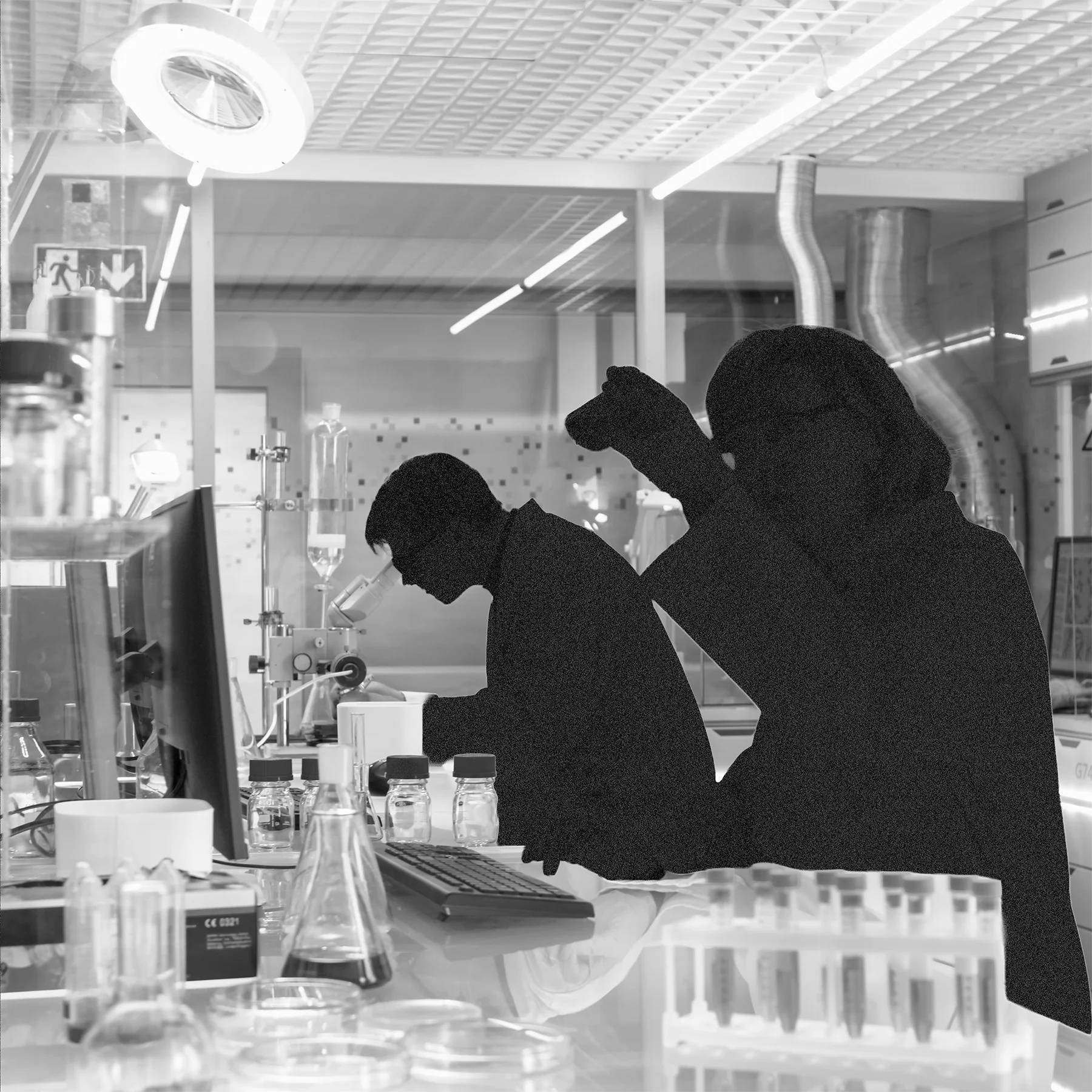 Black-and-white laboratory with two grainy, dark human silhouettes in the foreground. One bends over a workbench while the other holds a small object. Bottles, glassware, test tubes, and lab equipment fill the space.
