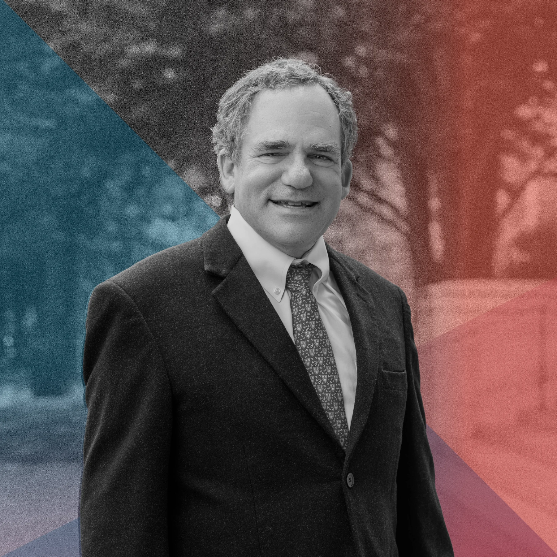 Black-and-white portrait of smiling man with wavy hair, dark suit jacket, white shirt and patterned tie. He's standing outside in front of a staircase and tree. Translucent overlays in teal and red form diagonal shapes across background of blurred trees.