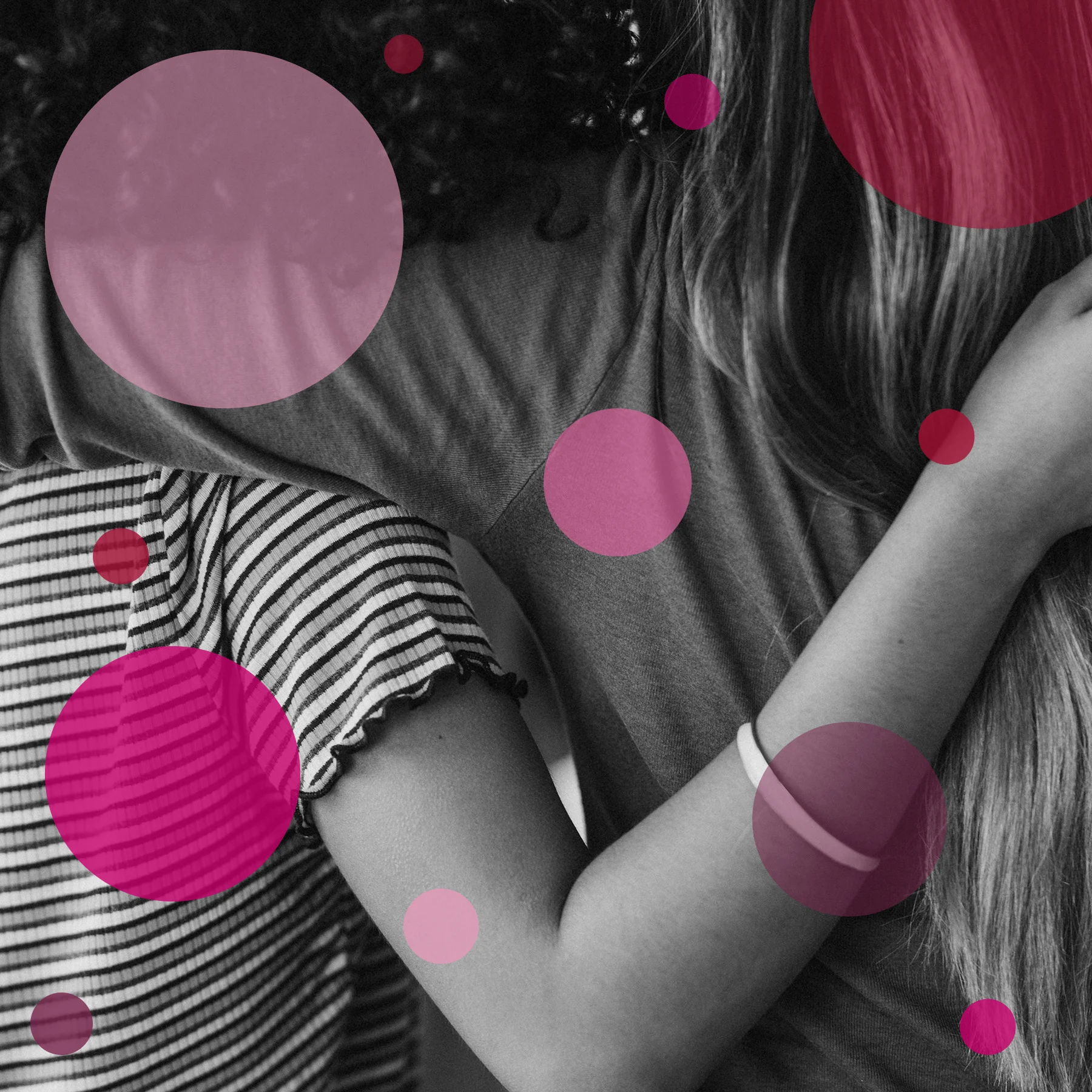 Close up on two young women standing side by side with their arms around each other's backs.