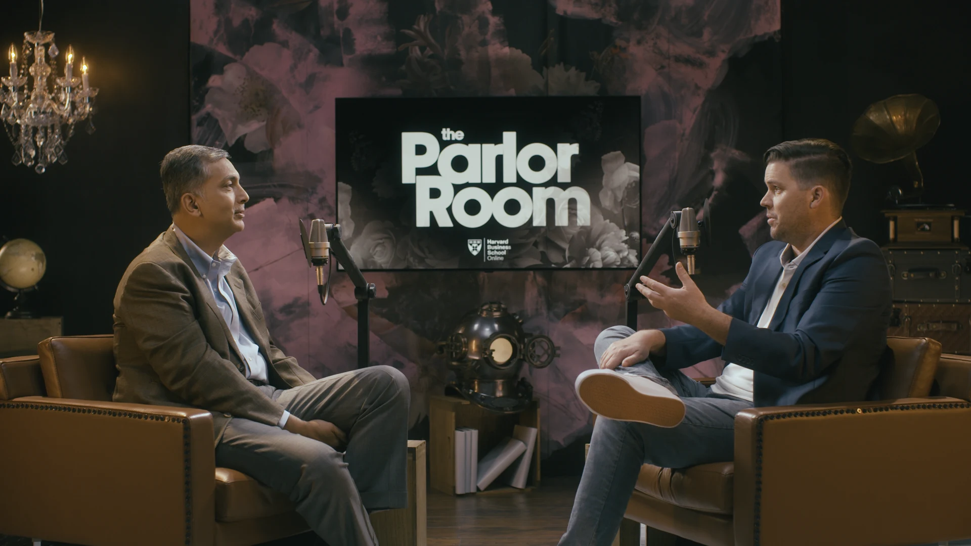 Host Chris Linnane seated with HBS Professor Mihir Desai on The Parlor Room set.