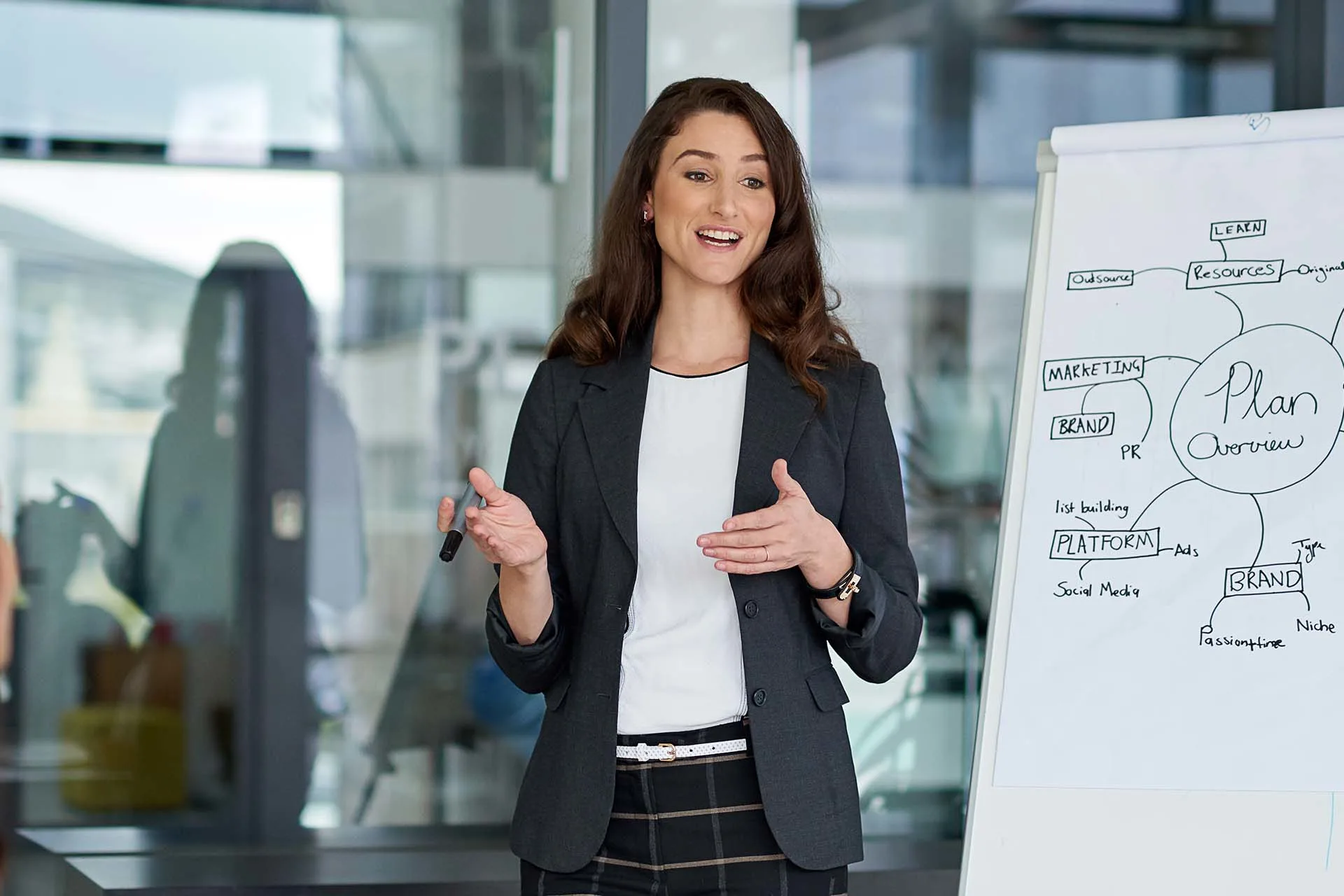 A female executive gives a strategy presentation on a white board