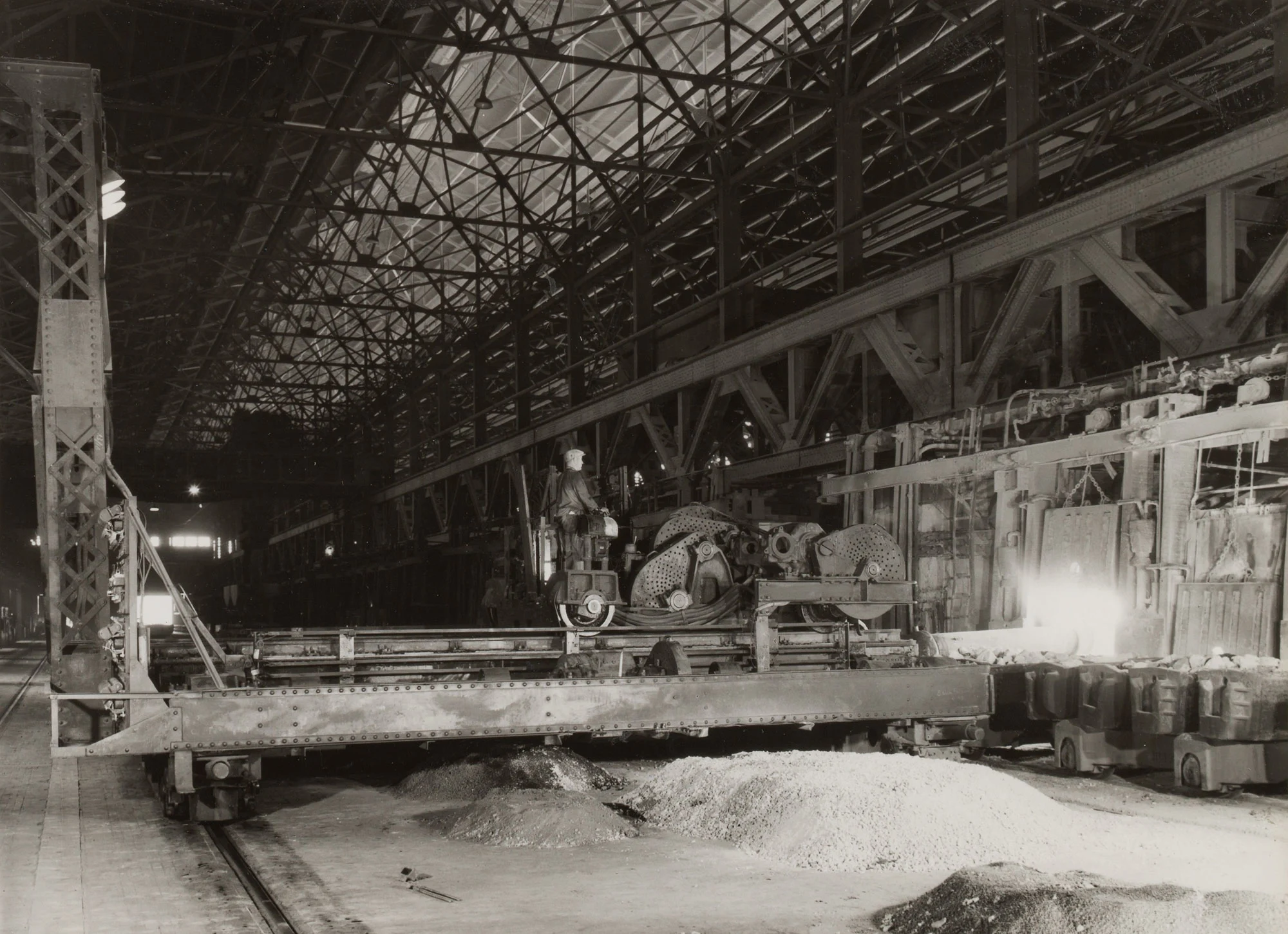 Charging machine dumps materials into No. 88 furnace at Gary Steel Works, with slag and dolomite piles in foreground.