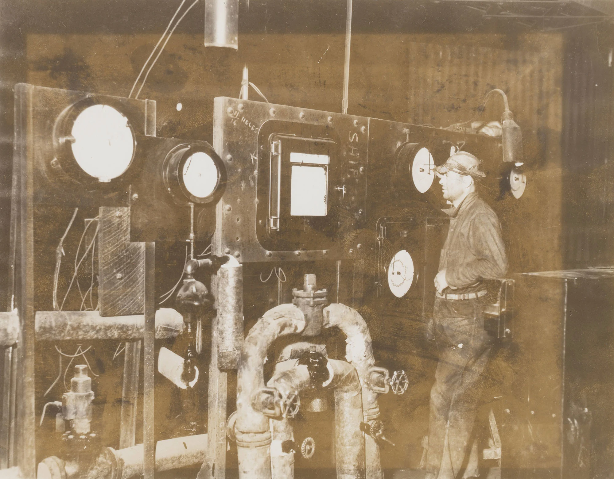 Worker checks electric eye control dials to monitor open hearth furnace temperature at Gary Steel Works.
