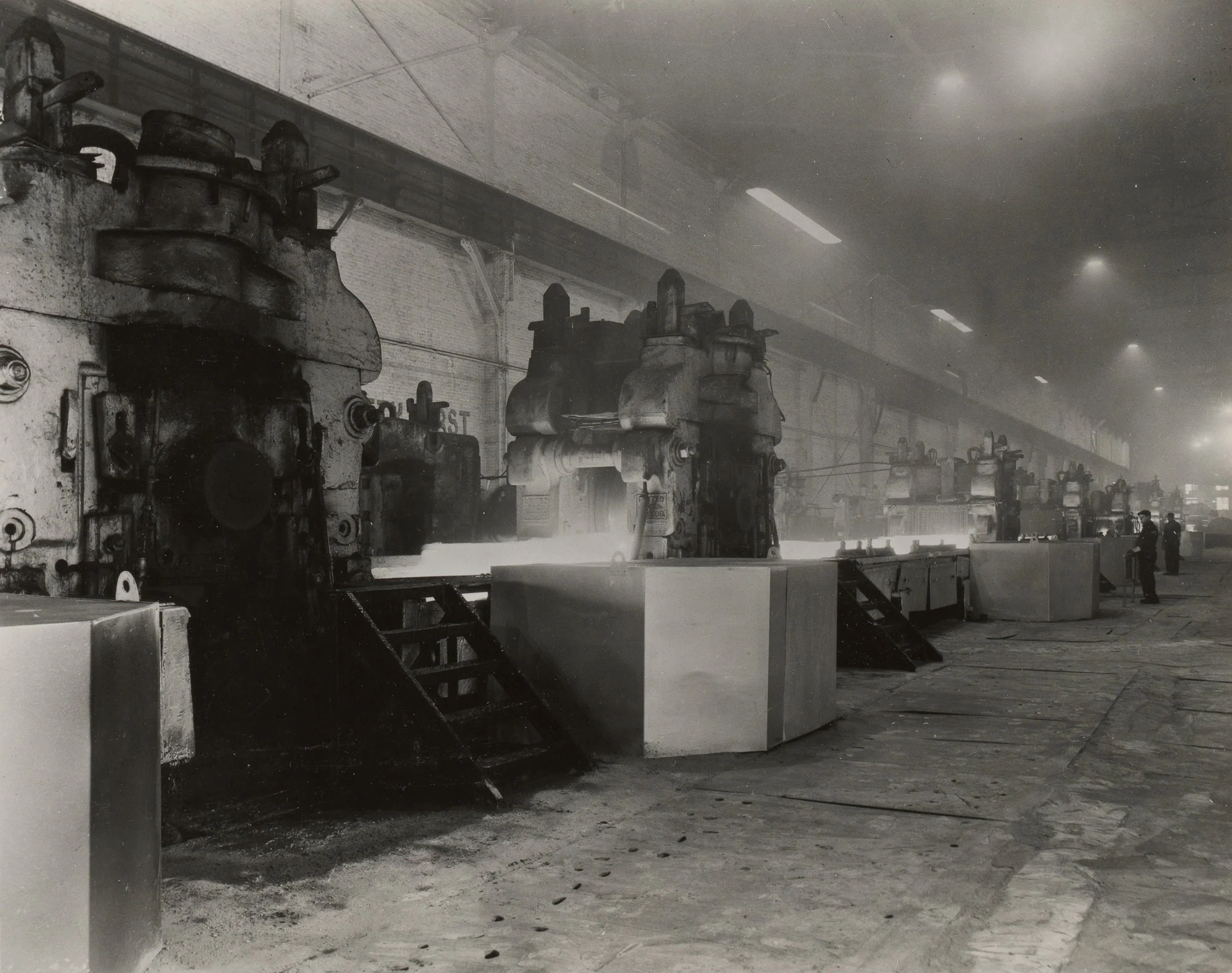 Rows of rolling stands process hot steel billets in intermediate stage at Gary Steel Works billet mill.