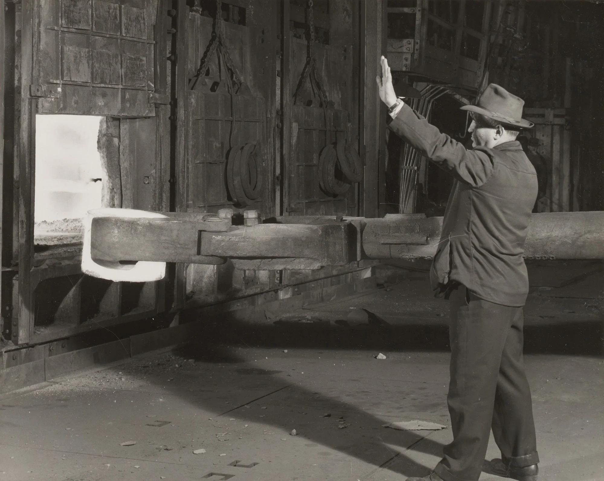 Supervisor signals crane as red-hot 930-pound wheel block is removed from furnace at Gary Steel Works.