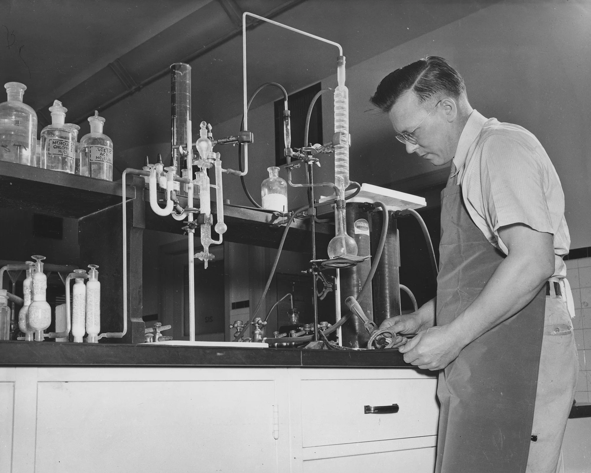 Lab technician works with glassware and chemical apparatus in the control laboratory at Oliver Iron Mining Company in Duluth, Minnesota.