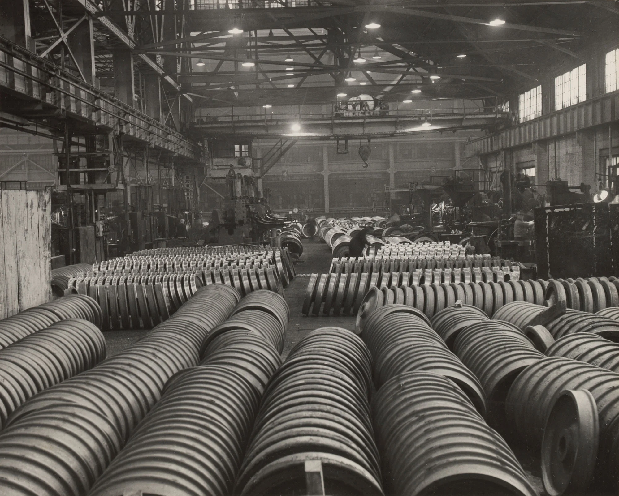 Rows of unfinished railroad wheels in foreground with finished wheels stacked in background at Gary Steel Works.