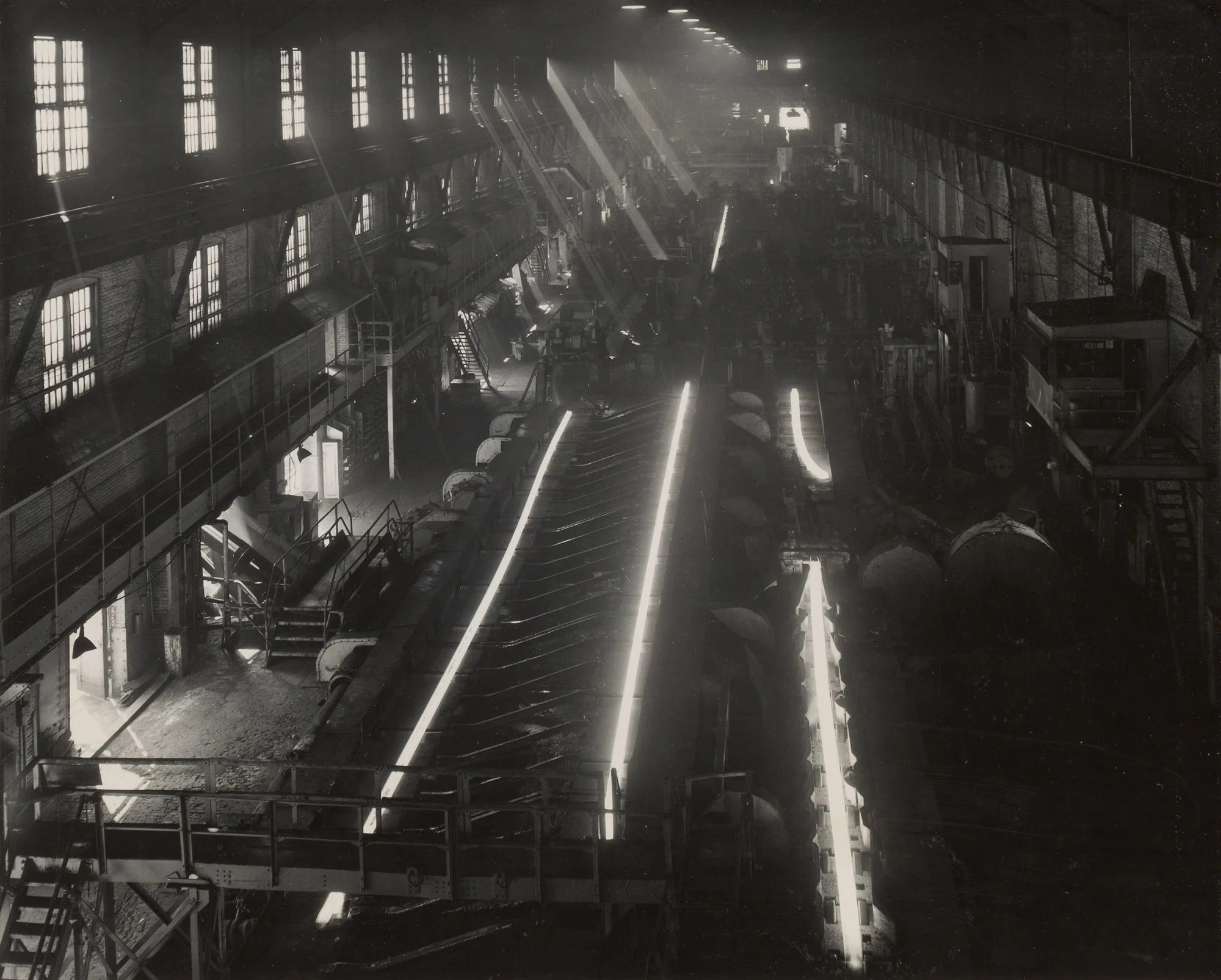 Interior of rail mill at Gary Steel Works showing glowing steel rails in various rolling stages.