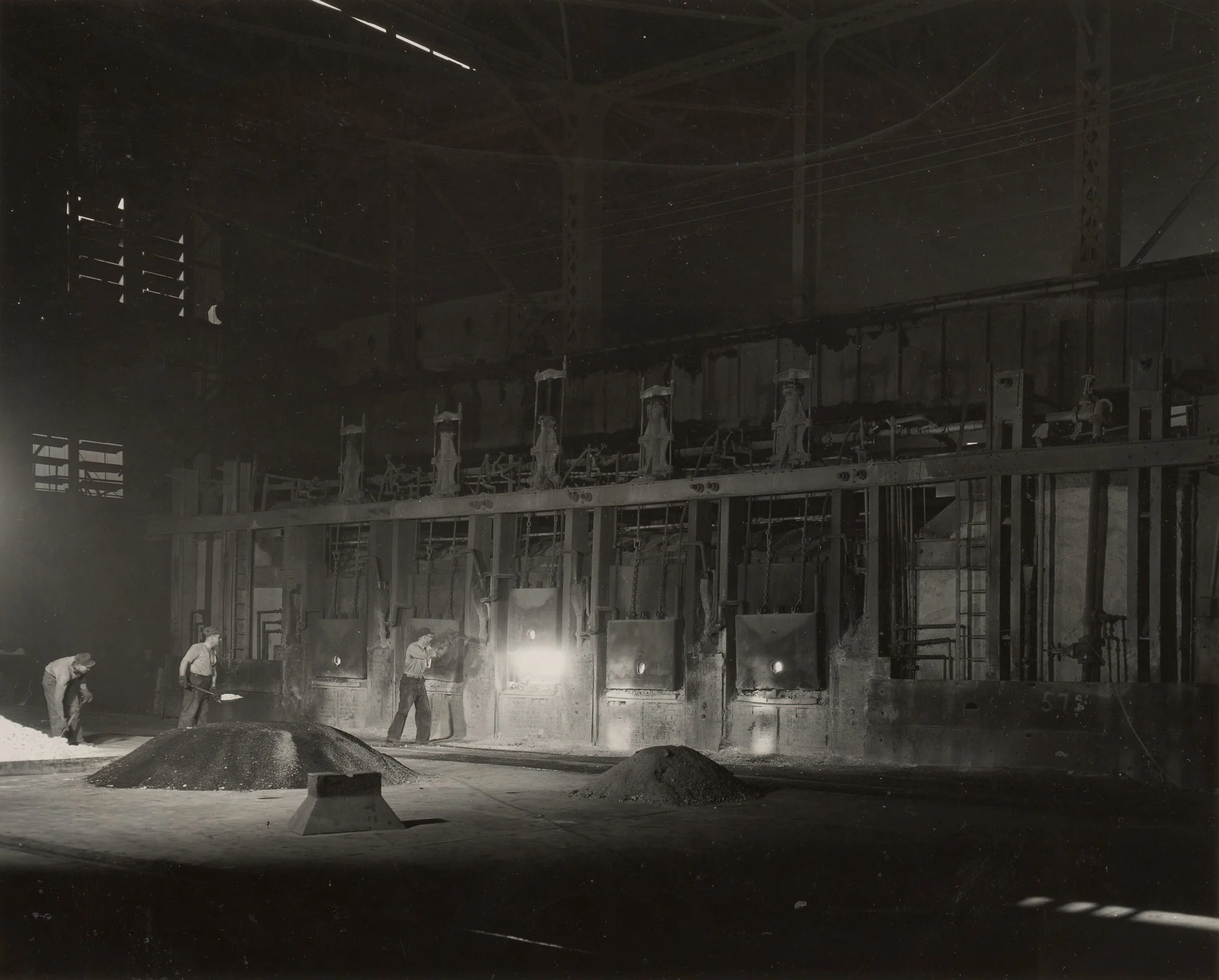 Workers shovel dolomite into open hearth furnace during bottom-making process at Gary Steel Works.