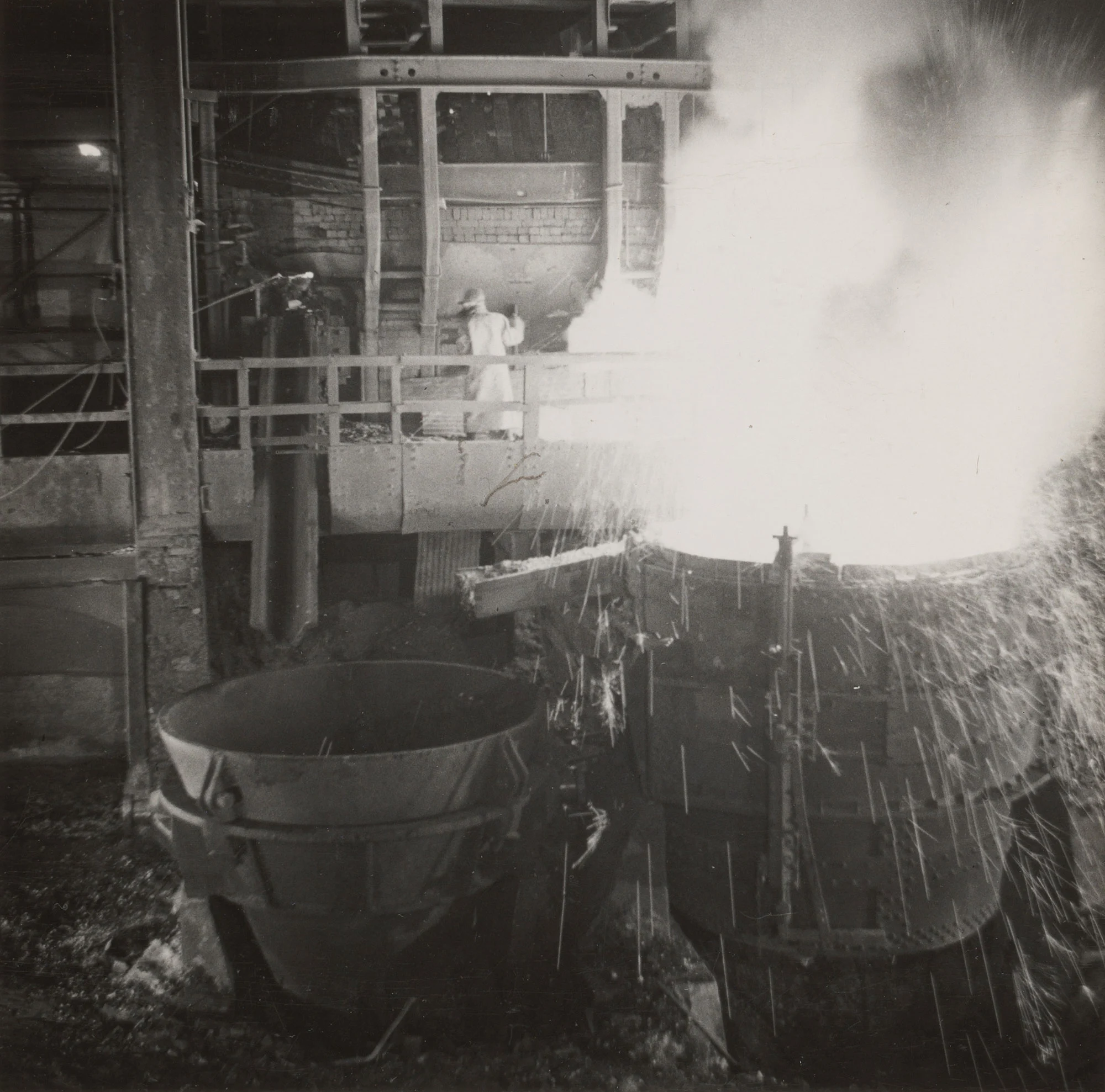 Bright sparks fly as molten steel pours from open hearth furnace during tapping at Gary Steel Works.