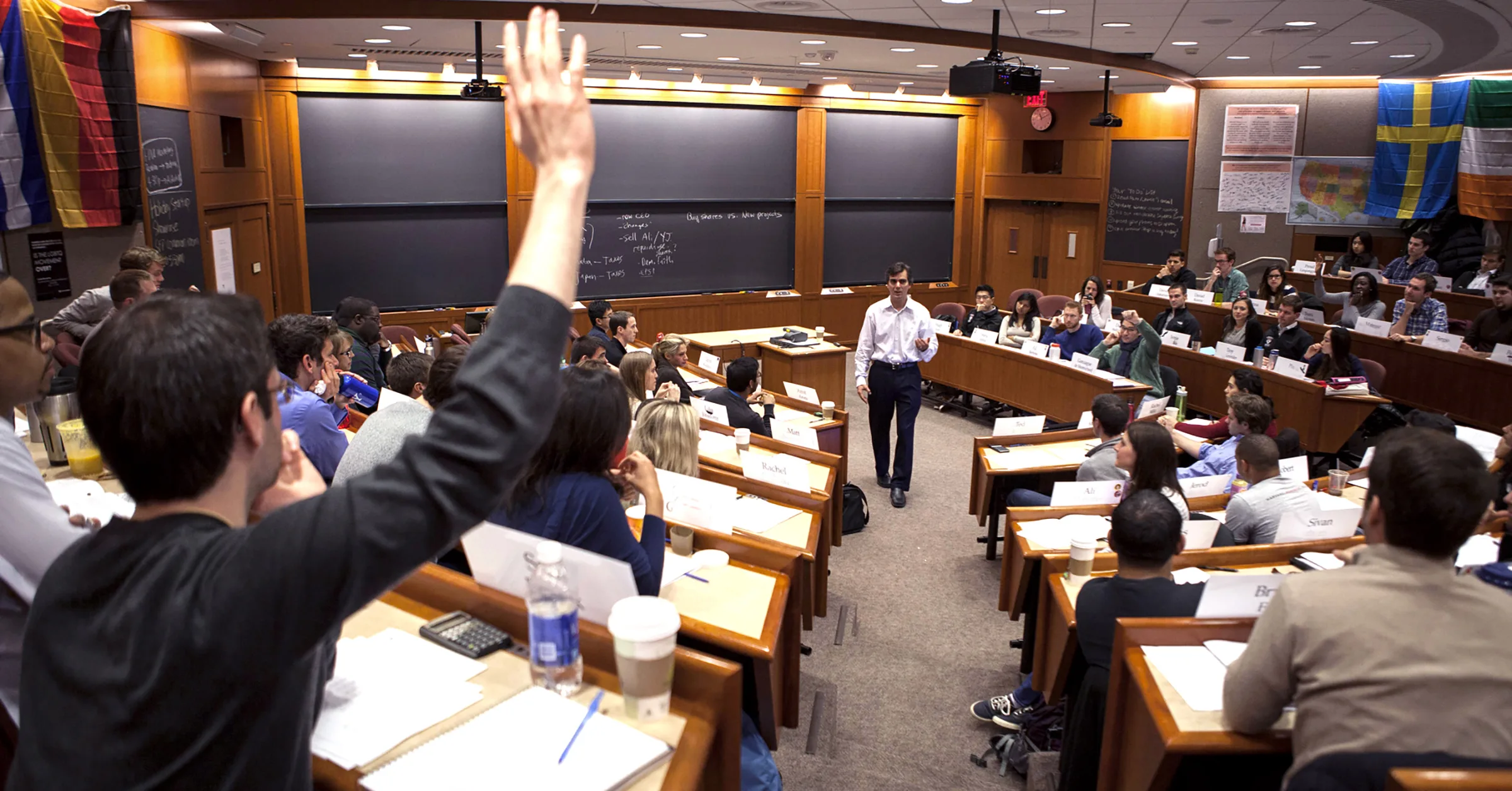MBA students raising hands in classroom during a case discussion