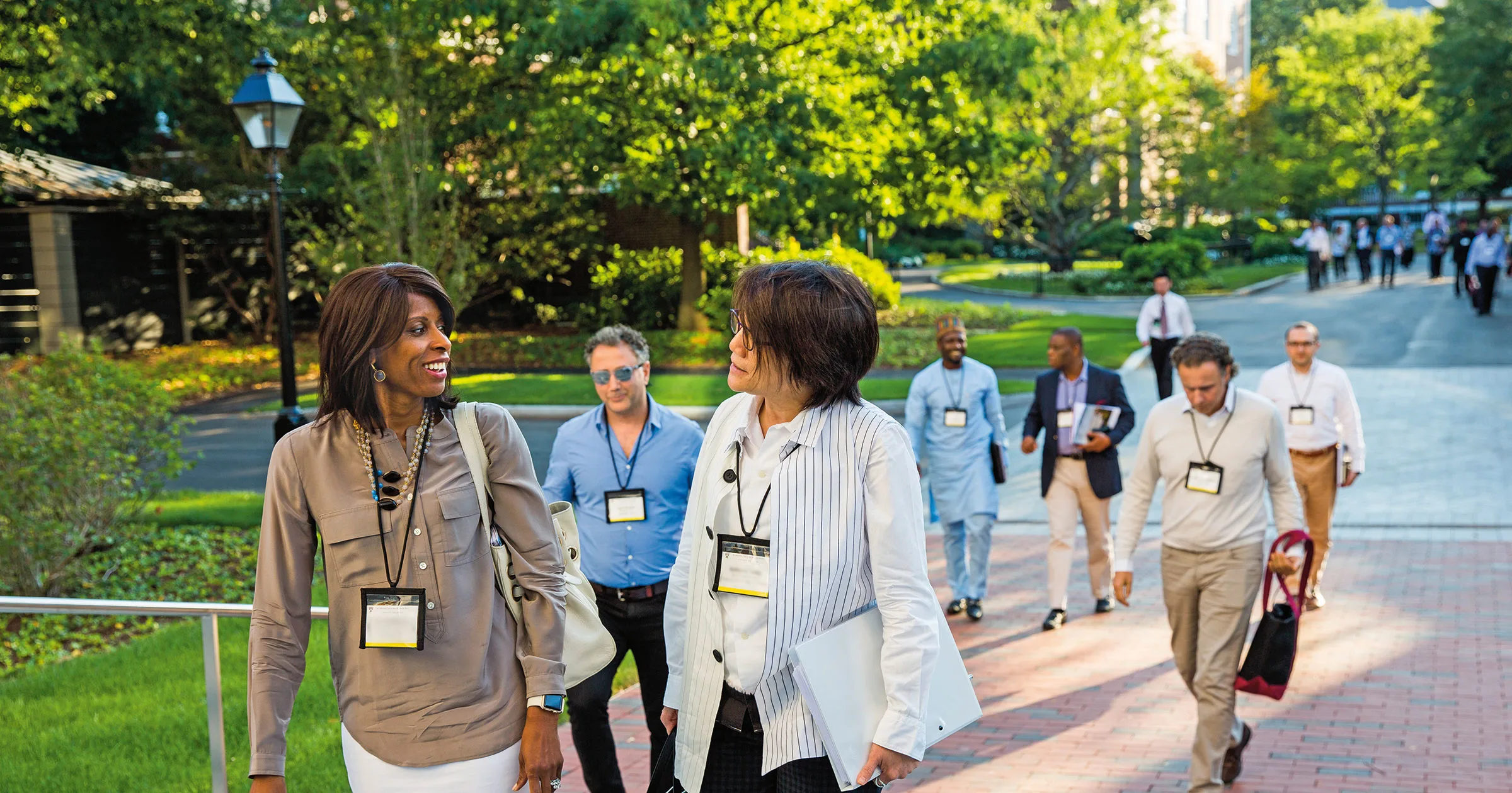 A diverse group of group of participants walking on HBS campus engaging in conversation 