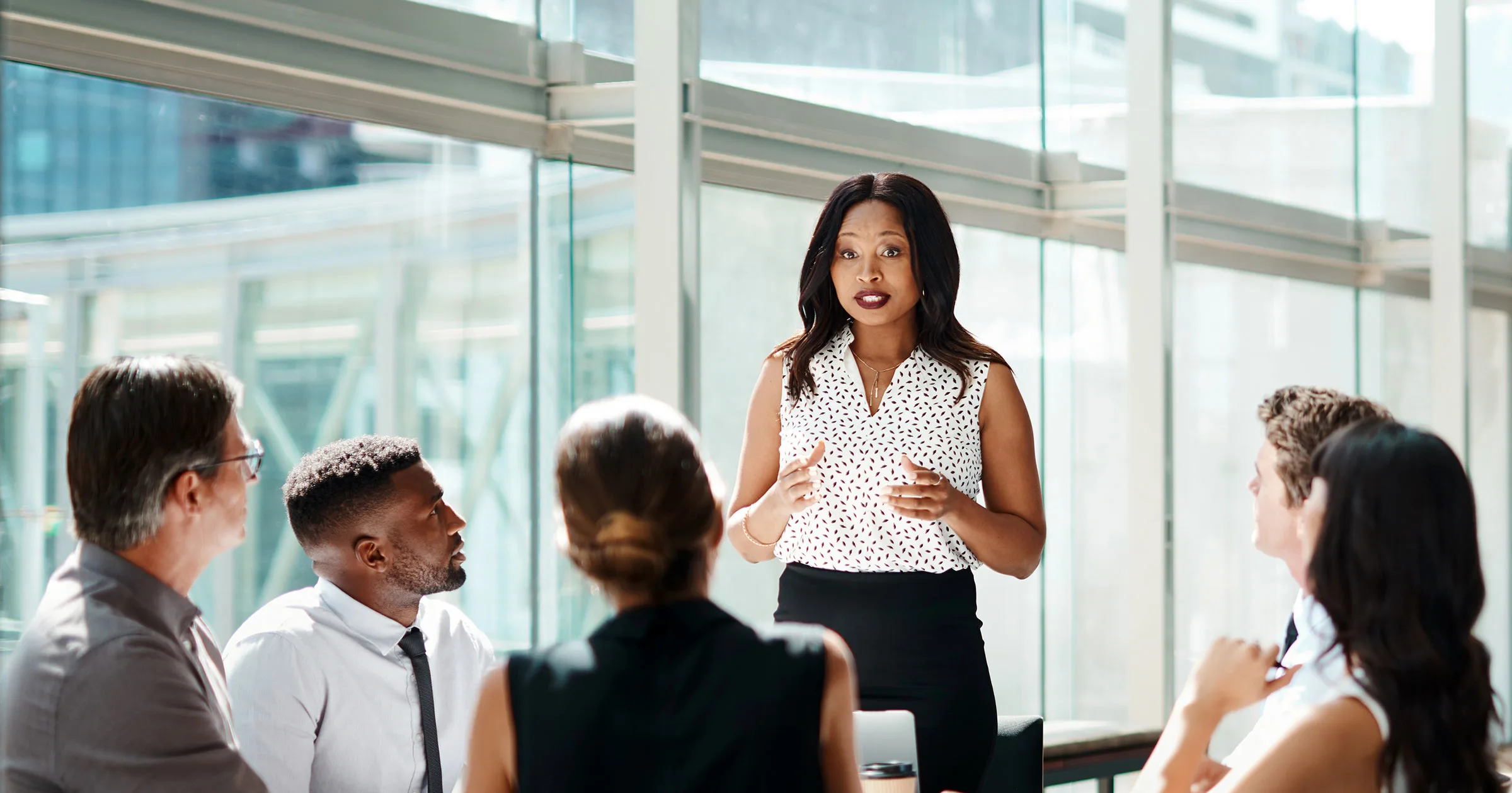 Diverse group of executives in a discussion in a modern office with large windows and natural light
