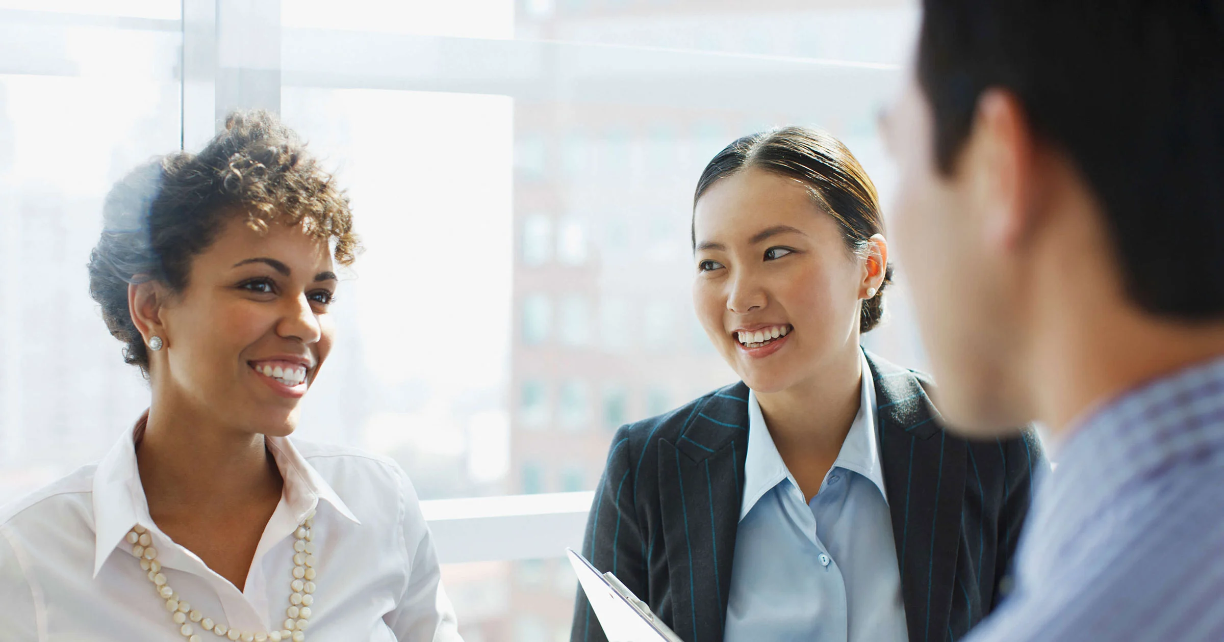 Executives in group discussion with large windows in background
