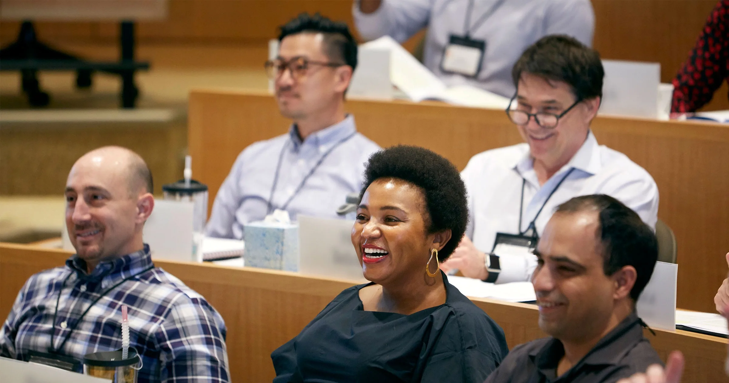 A diverse group of executives laughs and engages in HBS exed classroom during a training session