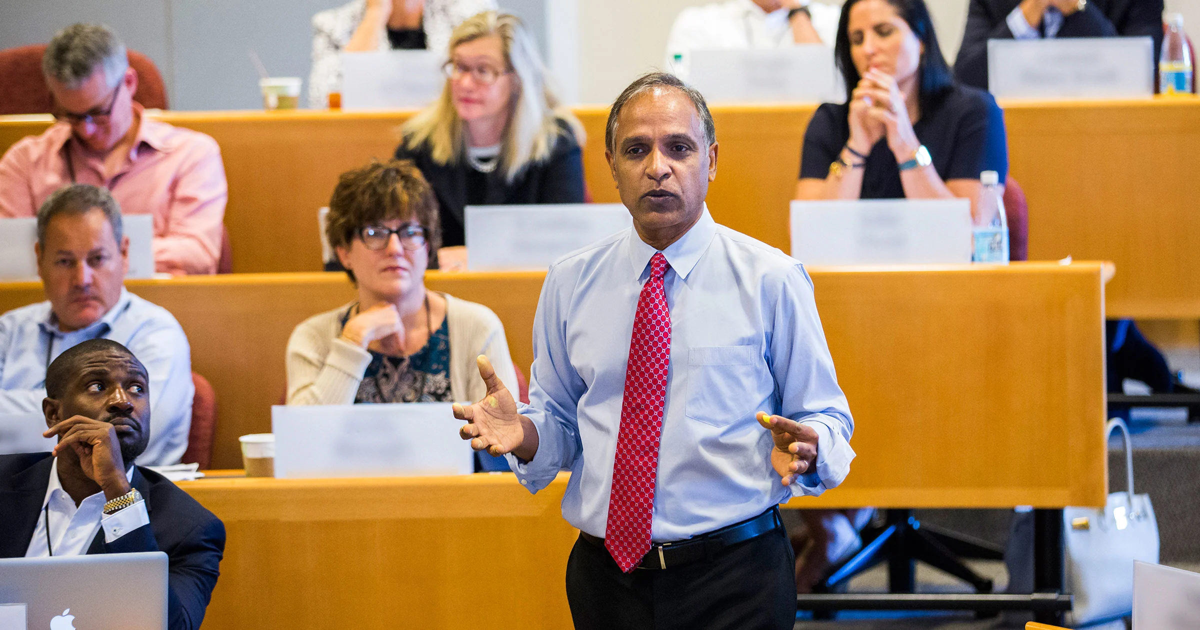 Faculty member Krishna G. Palepu giving lecture in HBS classroom with participants in background