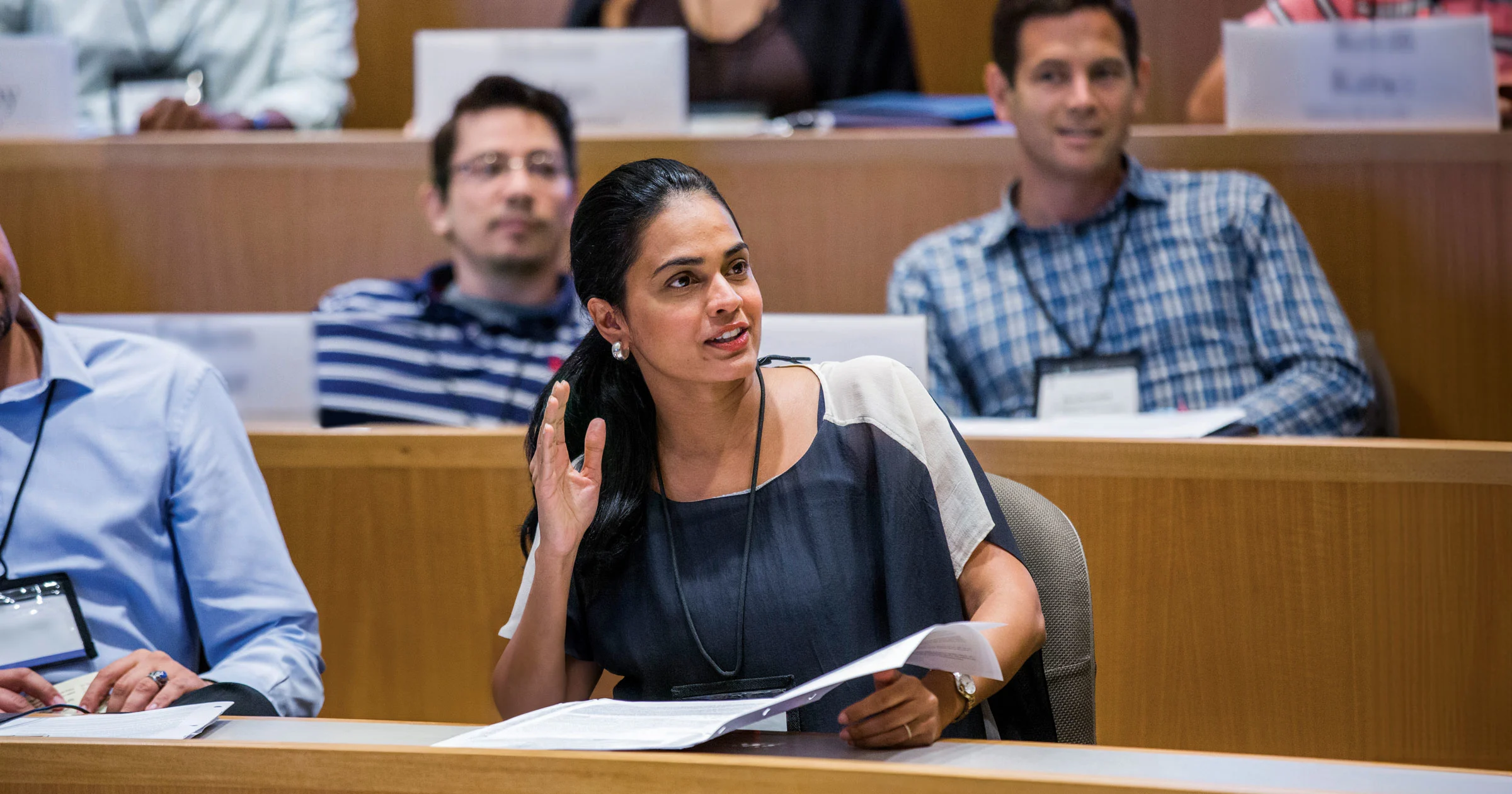 Female executive raises hand to participate in classroom lecture discussion