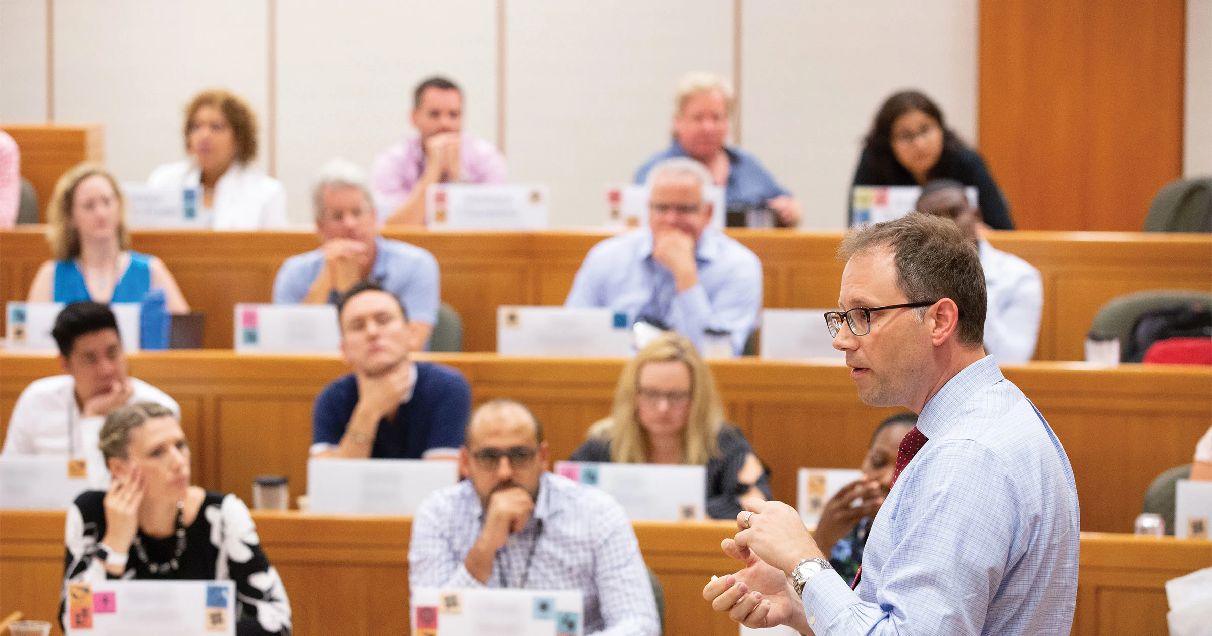 Side view of faculty presenter in HBS classroom with executive students in the background