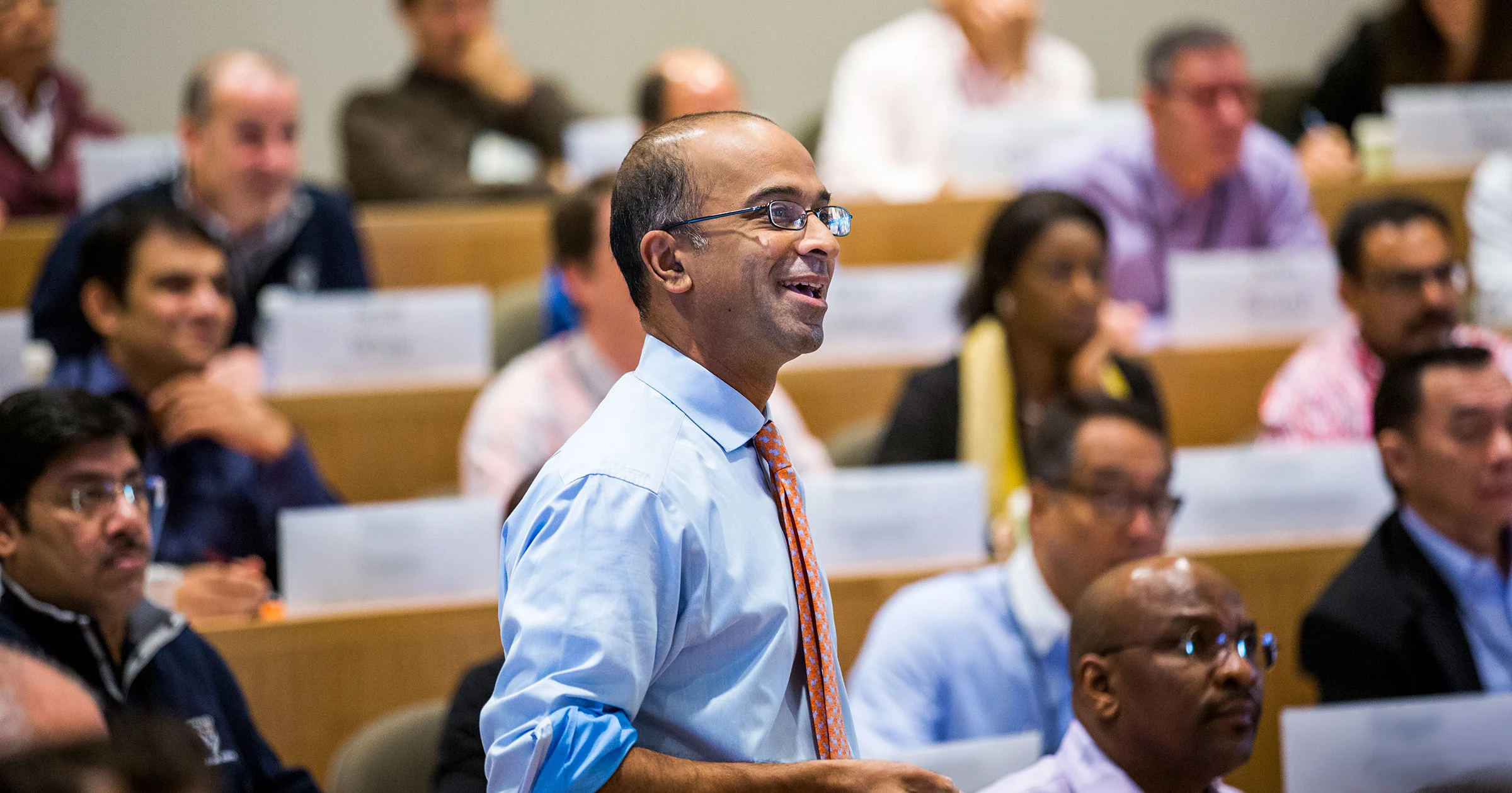 Close up of faculty member with executives sitting in background