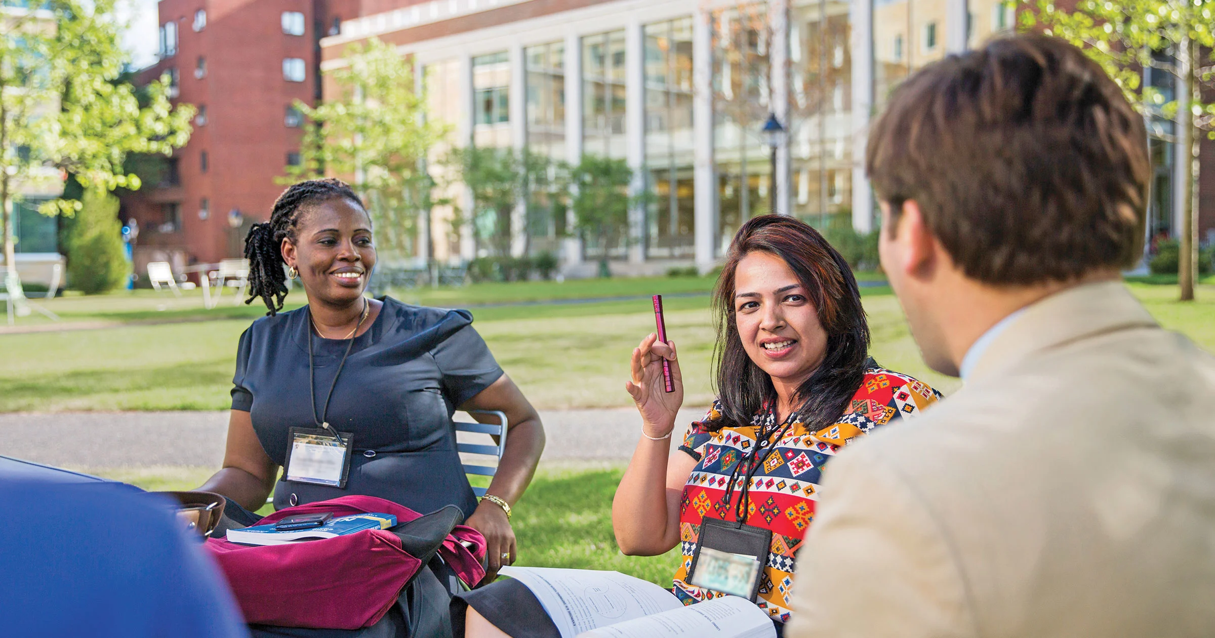 Harvard executive education participants engaged in discussion on HBS campus with Klarman hall in background