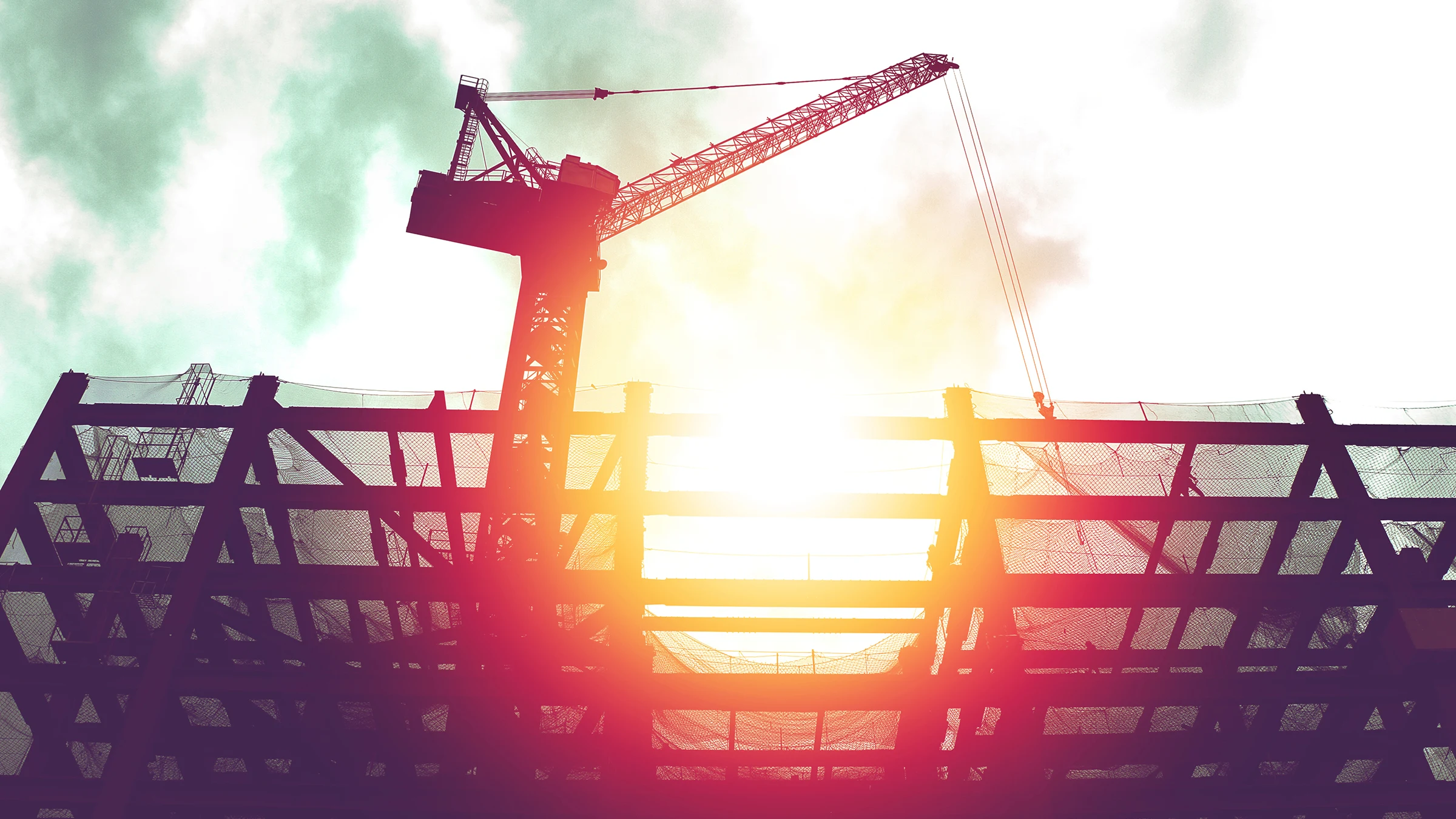Silhouette of crane in building construction site with sunlight