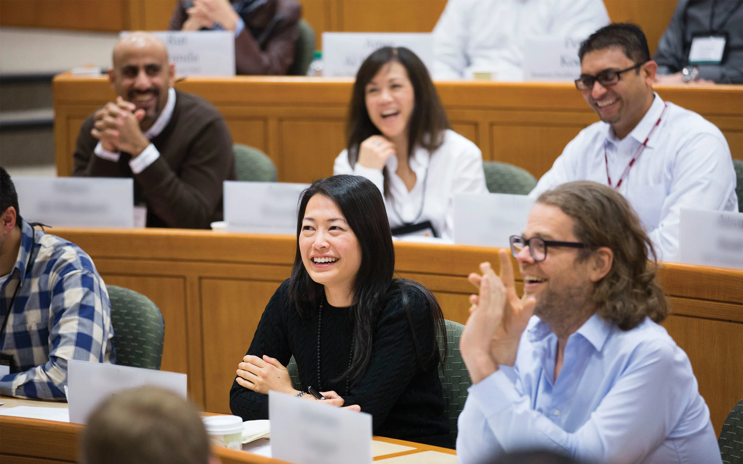 A group of executives in HBS classroom, engaged and laughing during a business program session.