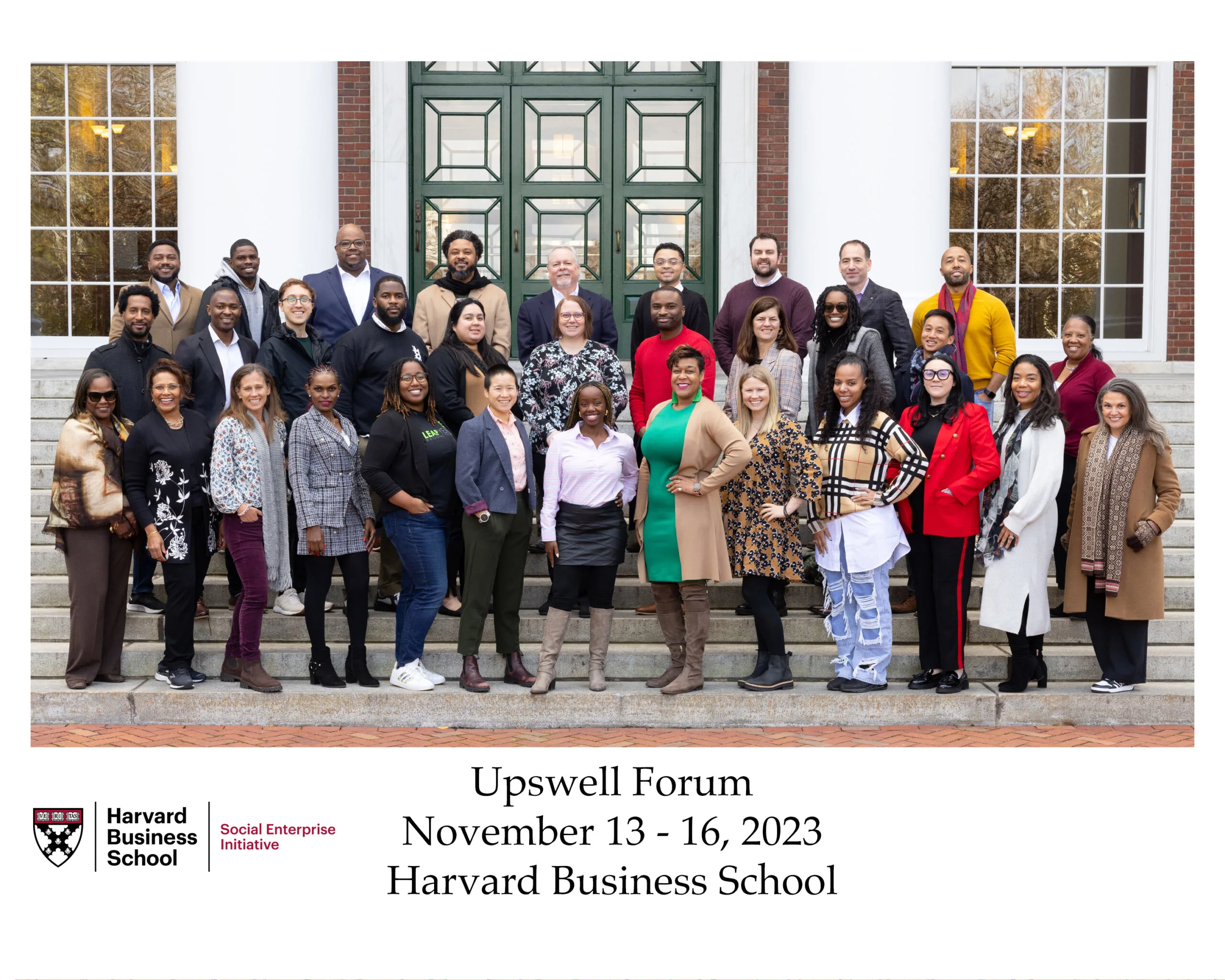 A diverse group of approximately 30 professionals standing on the stone steps of a building at Harvard Business School. The group is posing for the Upwell Forum event (November 13-16, 2023). Attendees are dressed in business casual attire.